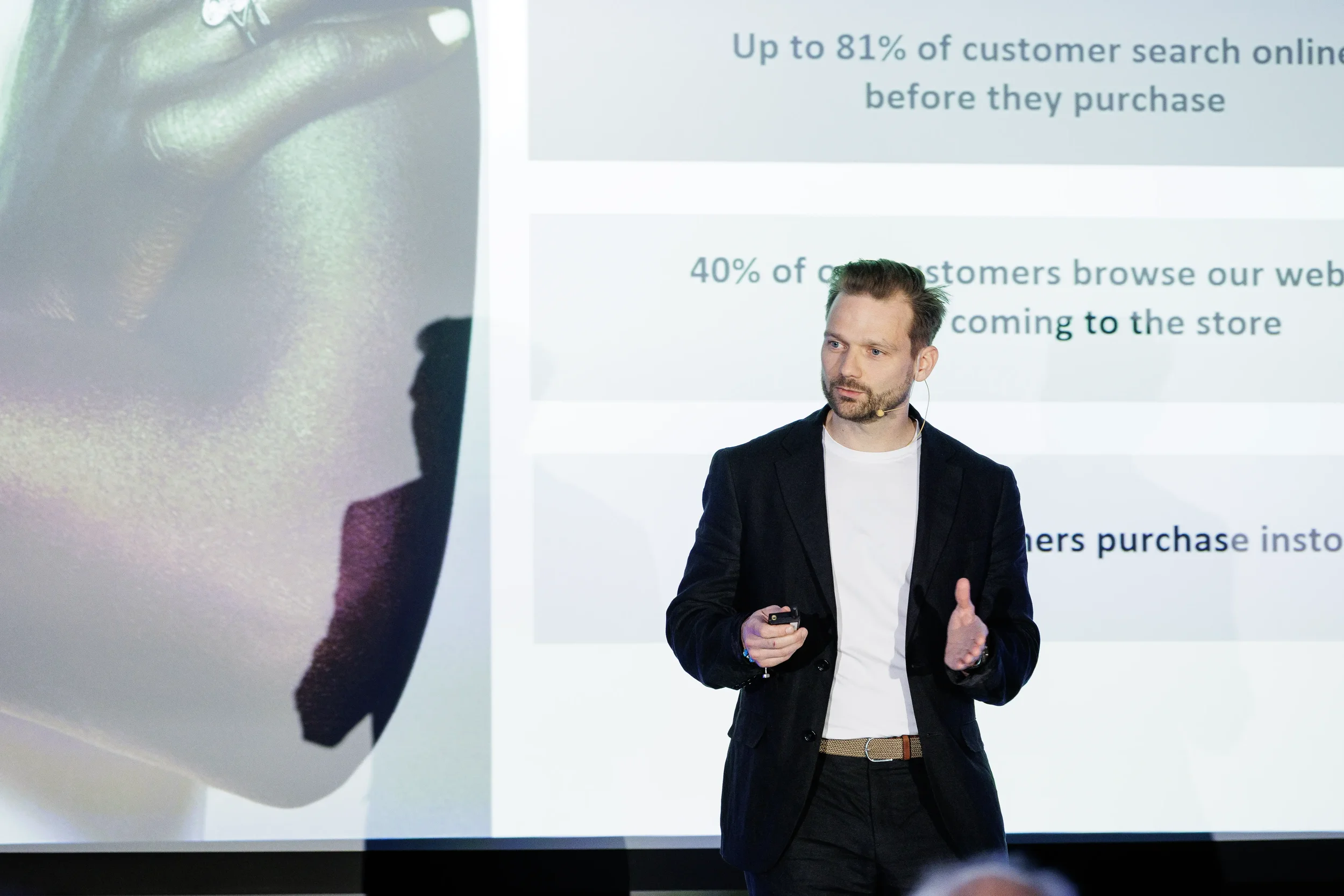 Speaker in black blazer presents data slide on stage at Orlando corporate conference