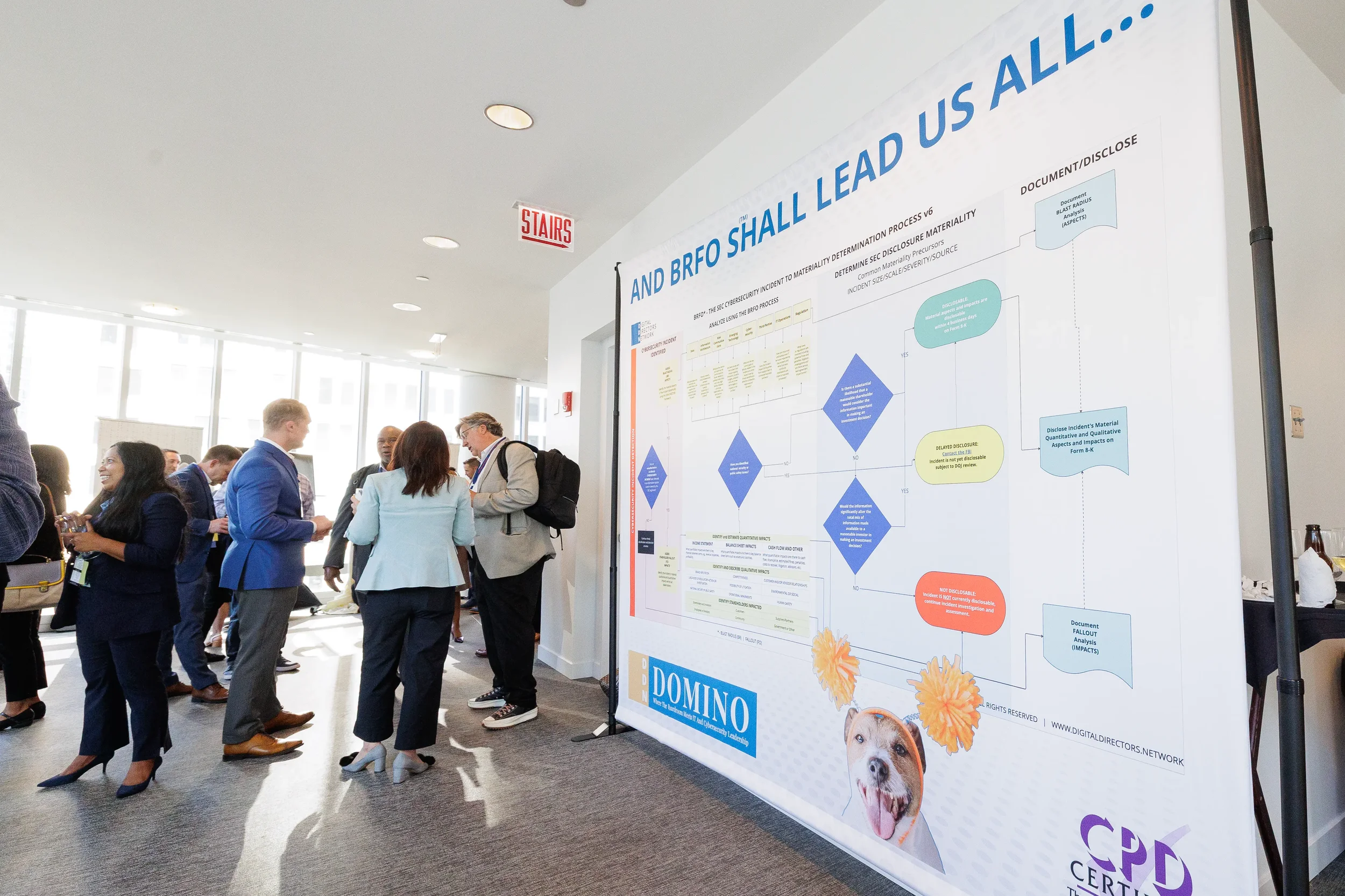 Attendees network near large branded diagram display board in hallway at Chicago industry conference