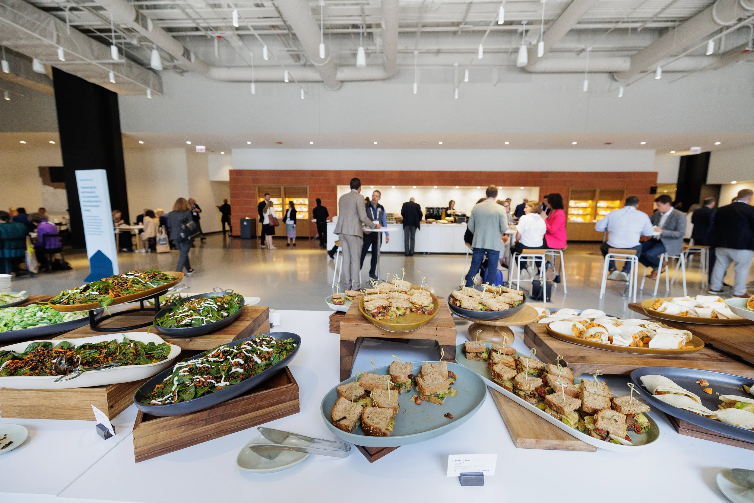 Buffet spread of sandwiches and salads with attendees mingling at Orlando corporate conference