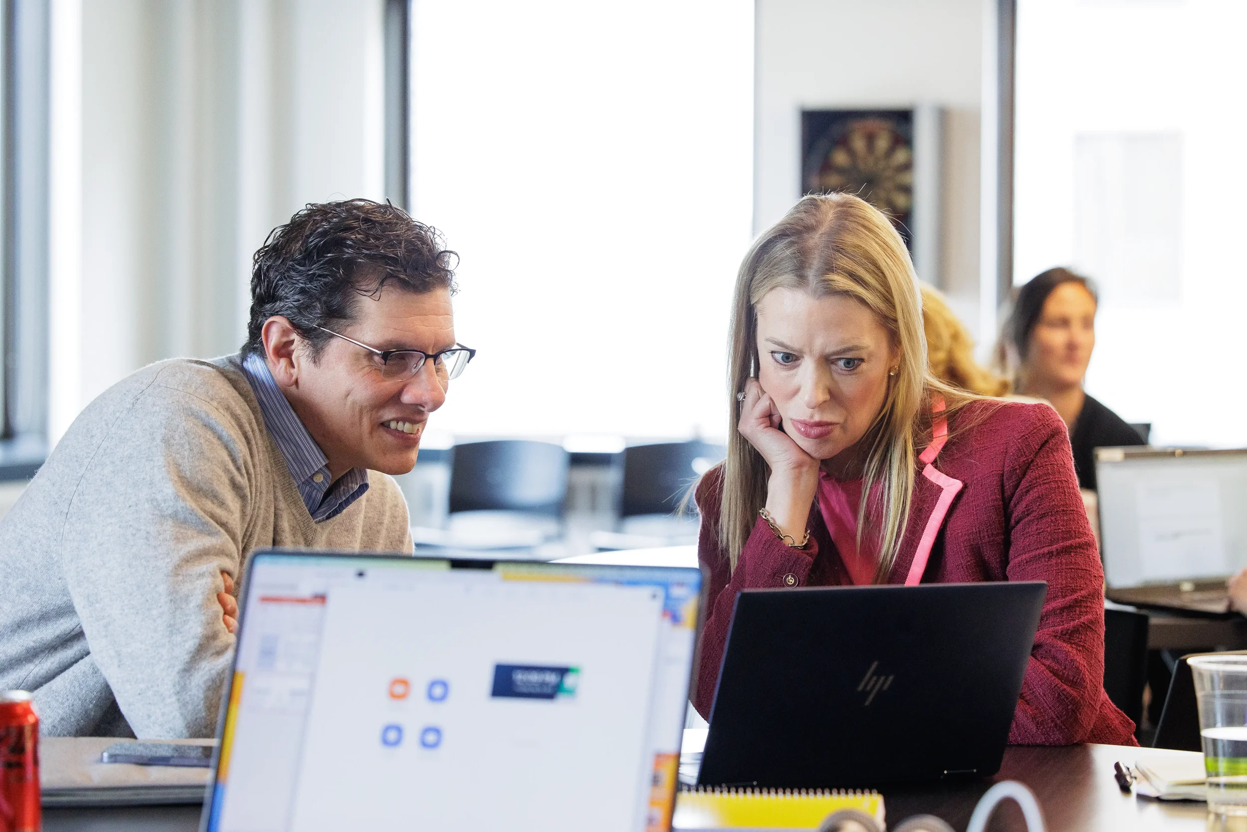 Two attendees lean in together to review content on a laptop during Orlando corporate event session