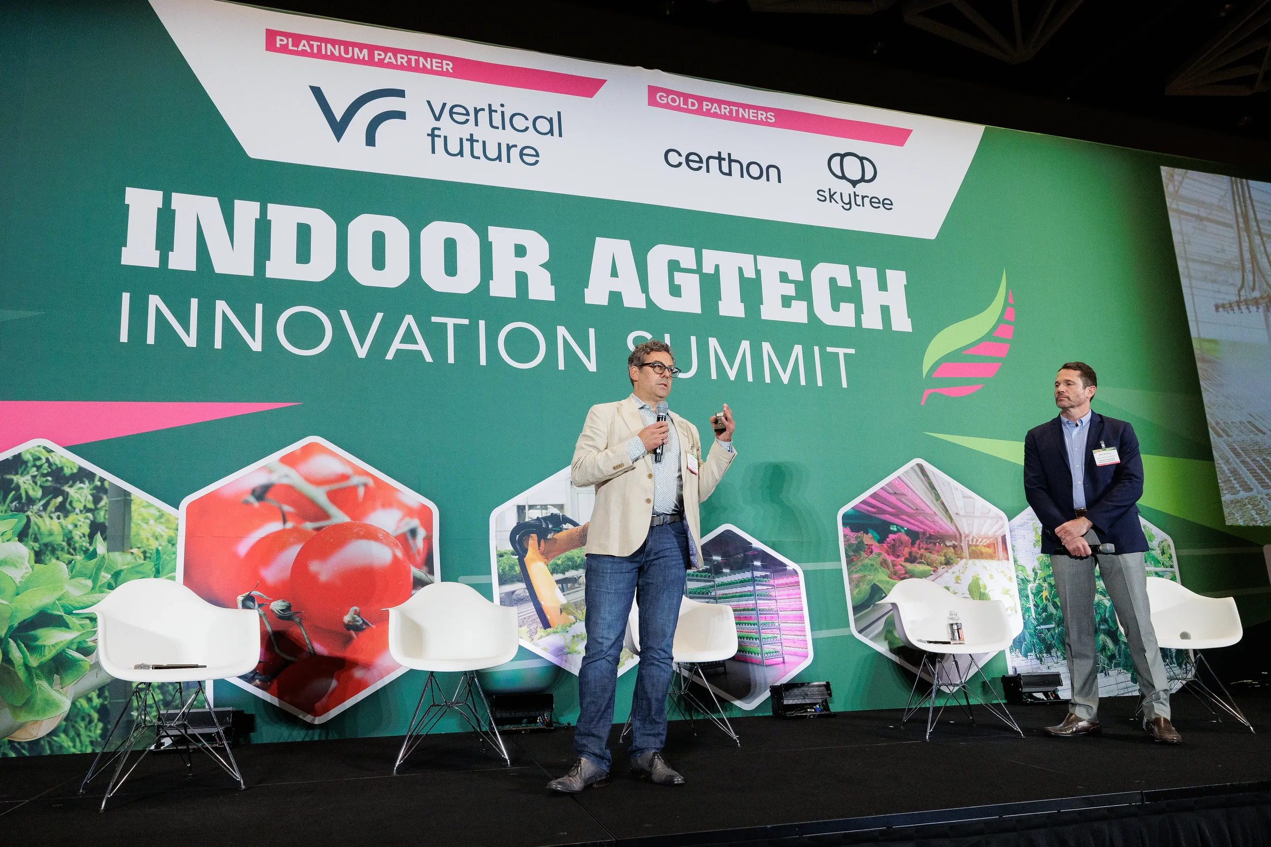 Speaker gestures while presenting on stage in front of branded backdrop at Orlando industry conference