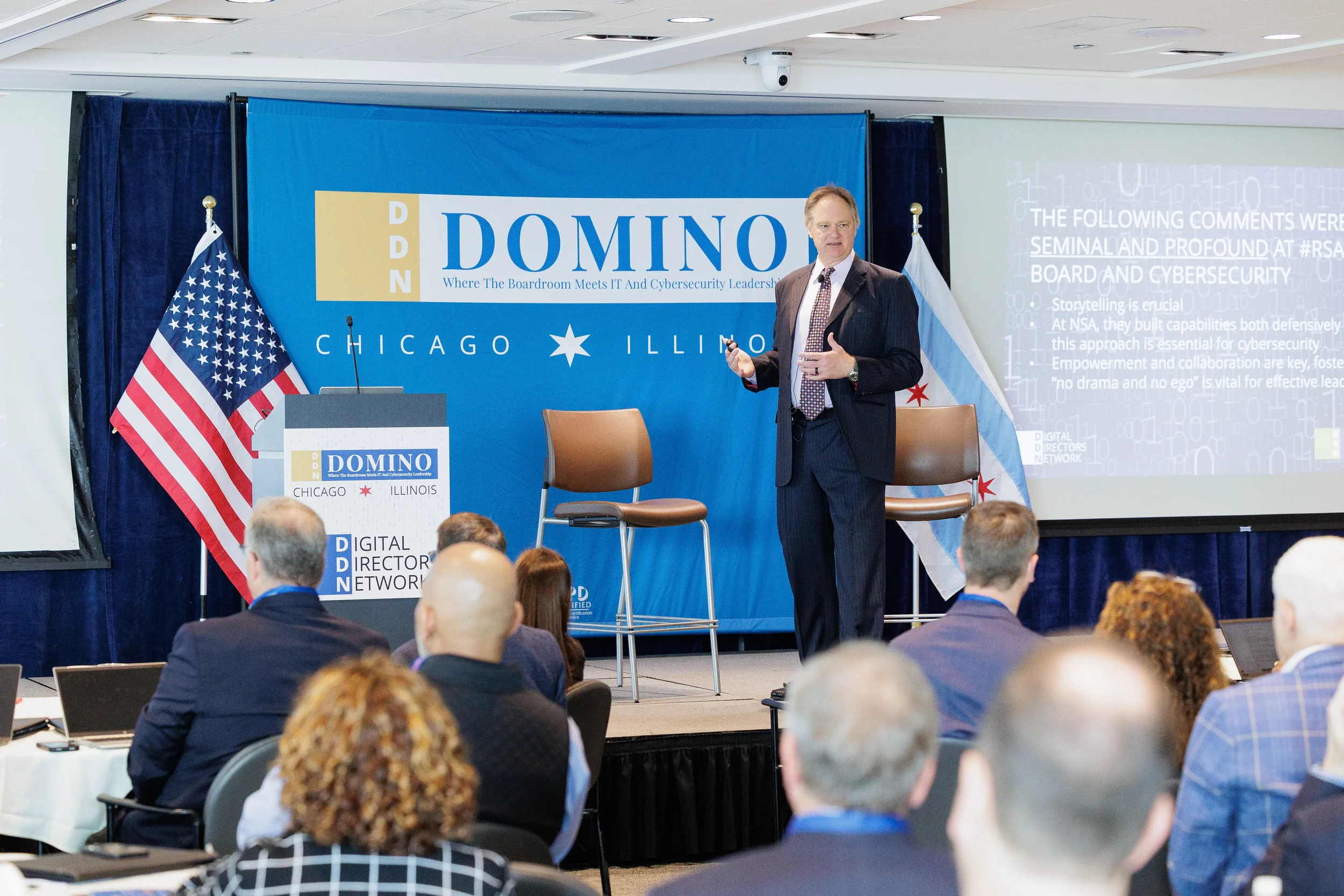 Speaker presents from branded stage beside podium and Chicago flag to seated audience at Orlando corporate event