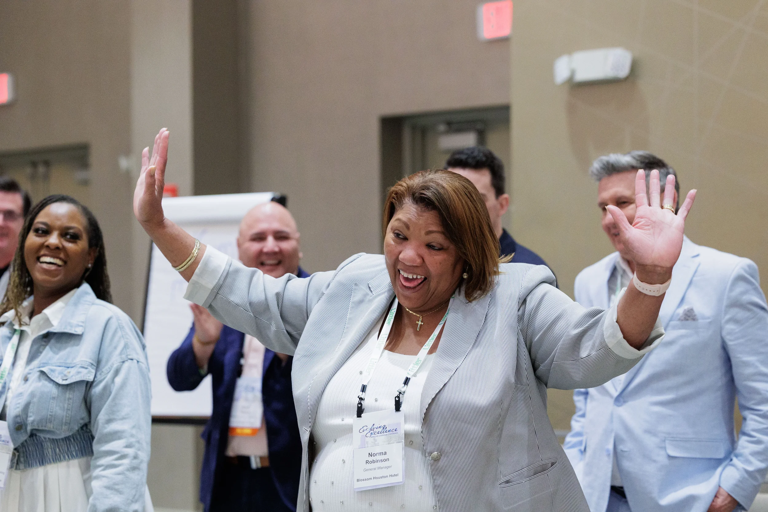 Attendee with lanyard raises arms enthusiastically during energetic group activity at Orlando corporate event