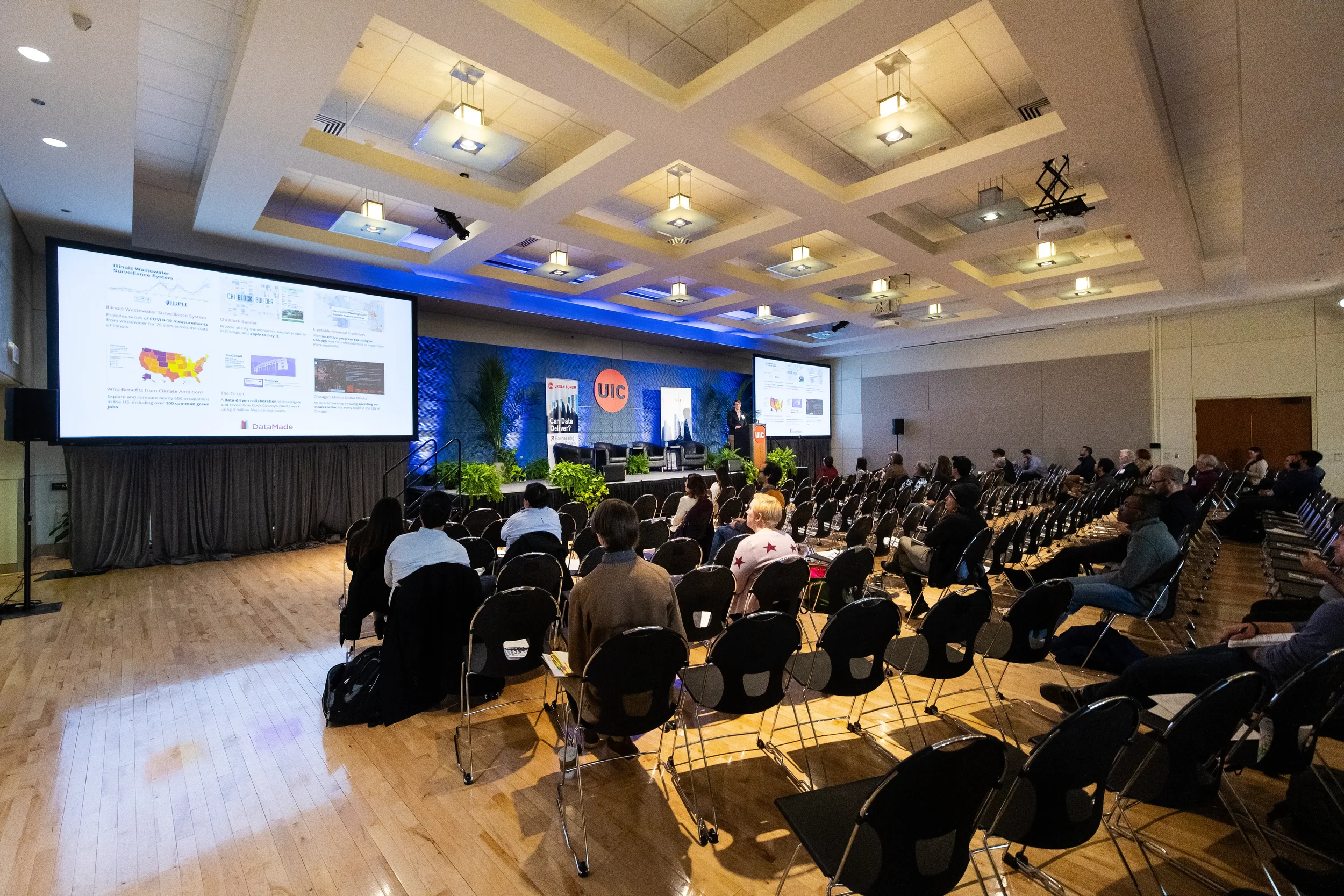 Audience watches speaker at podium with large projection screen at Orlando corporate conference