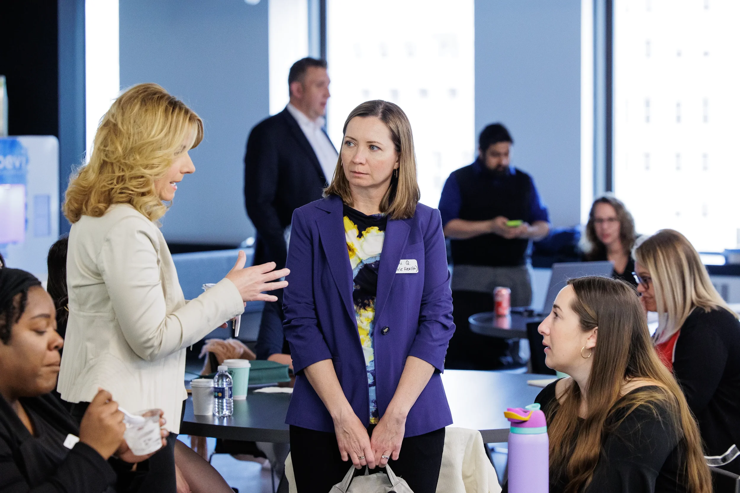 Two female attendees converse amid a busy room of people during a networking break at Orlando conference