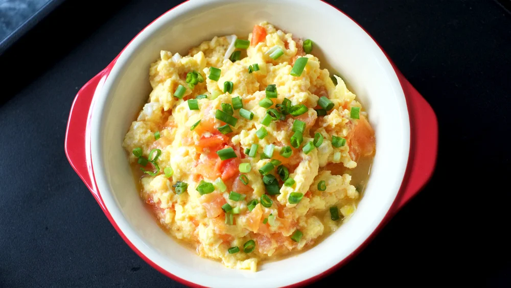 Stir-fried Tomato with Egg Prep time: 5 mins Cook time: 10 mins Total time: 15 mins Serves: 4 Ingredients: · 3 Eggs · 1 medium Tomato · 1-1/2 tablespoons Sugar · 1/4 cup Water · pinch of Salt · 2 tablespoons Vegetable oil Instructions: 1) Dice the tomatoes and set aside. 2) In a medium bowl, beat the eggs and throw in the pinch of salt to slightly season. 3) You are now ready to start cooking - heat up the oil in a pan and throw in the diced tomatoes, saute for a couple of minutes before adding the sugar and water, let the mixture simmer until the water has lessened to half its original amount. 4) At this point, pour the egg mixture over the tomatoes and start stirring and folding the mixture consistently. 5) After about a minute, turn the fire off and transfer the completed dish immediately onto a platter. 6) Serve with steamed white rice and enjoy!