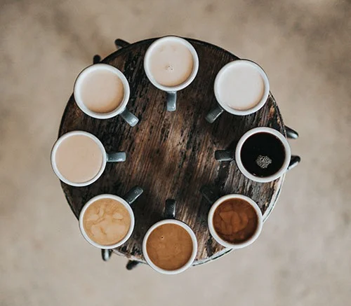 Group of eight types of teas laid out on a wooden table in a perfect circle
