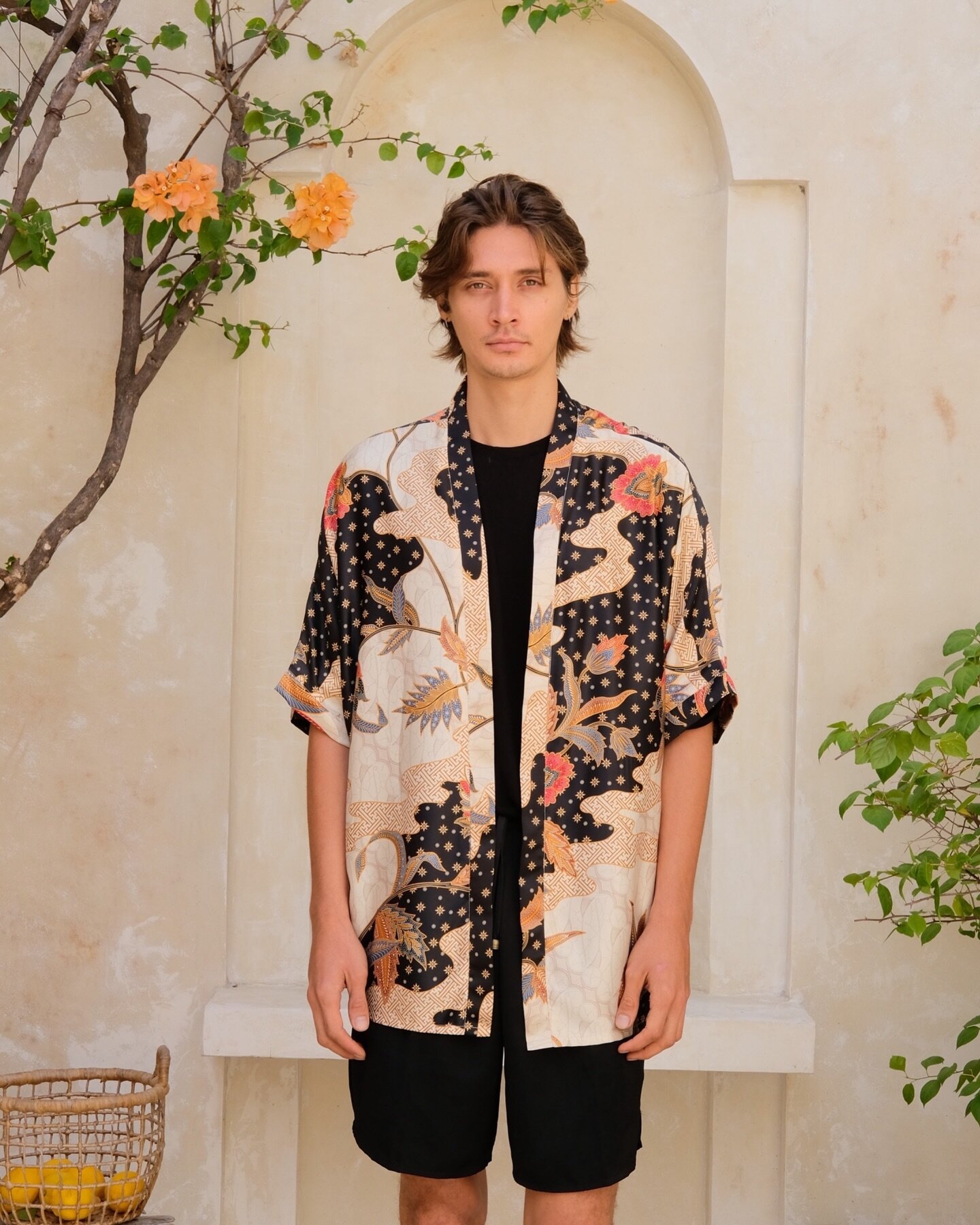 Our Ambra unisex kimono shirt comes in stunning black and earthy tones adorned with an intricate orange flower pattern. 

This unique piece seamlessly blends cultural flair with contemporary fashion and makes a statement in a subtle and classy way.

