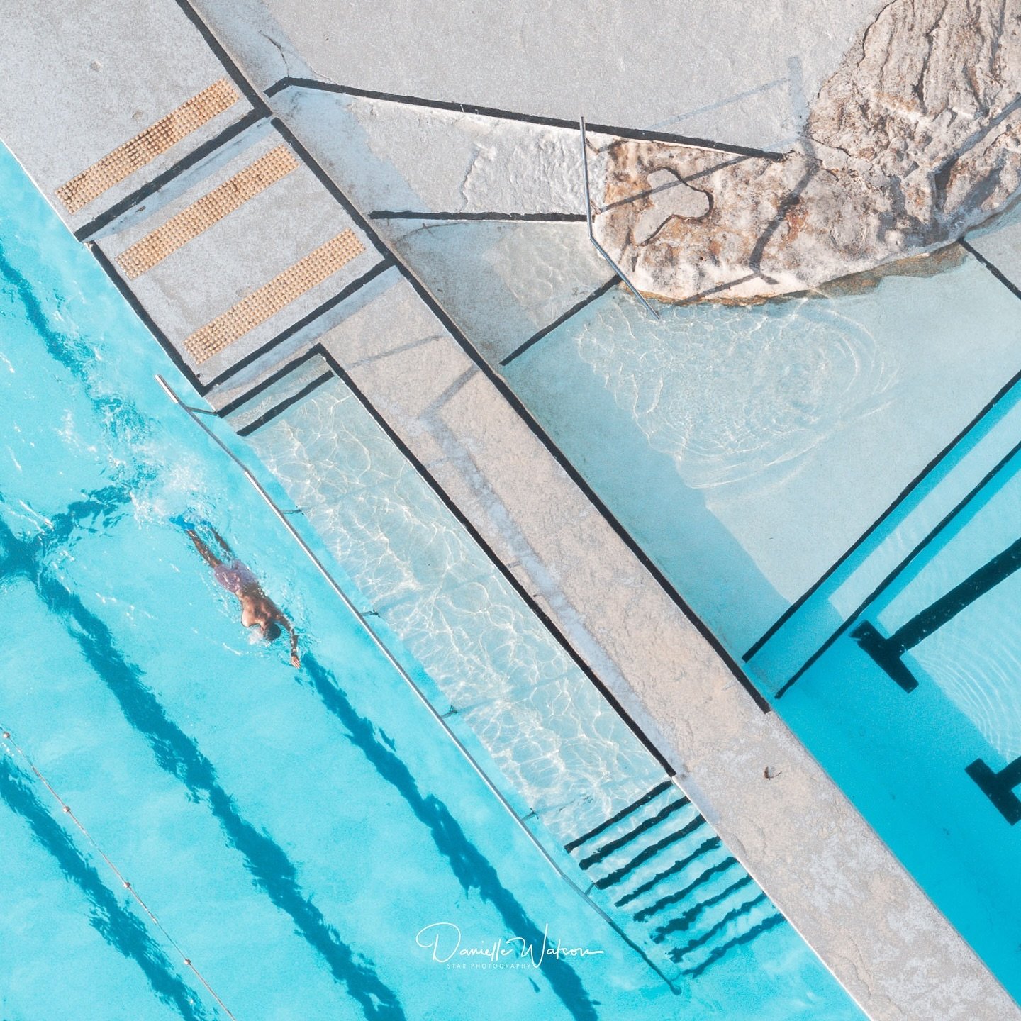 As the first light of morning gently brushes across Bondi Icebergs, the world feels calm and unhurried. The water glistens with soft turquoise hues, catching the interplay of sunlight and shadows. The crisp lines of the pool seem to guide my eye, con