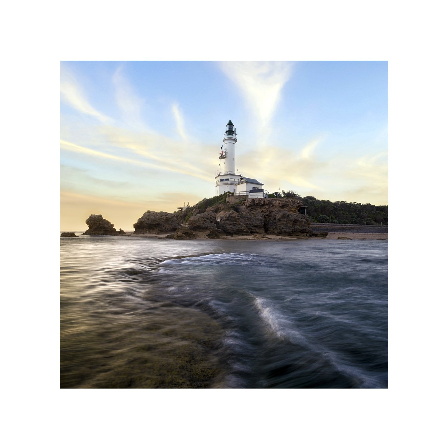 Lighthouse at sunset with cascading waves