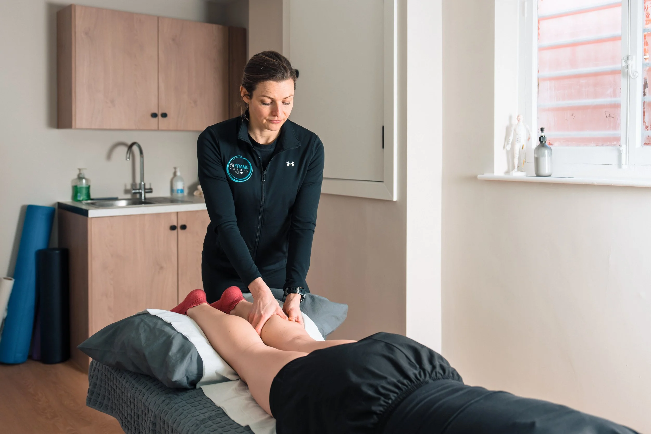 A woman receiving a massage from a massage therapist in a treatment room.