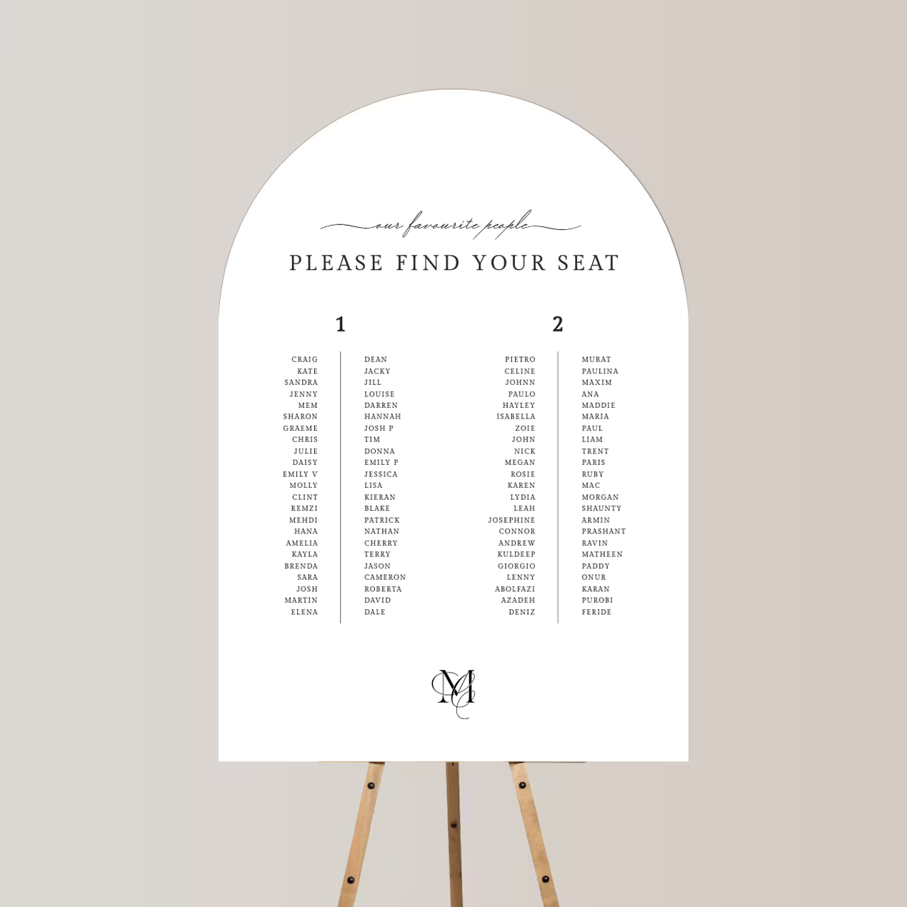 A printed seating chart for an event, listing names under two tables, with elegant script and serif fonts, mounted on a stand.