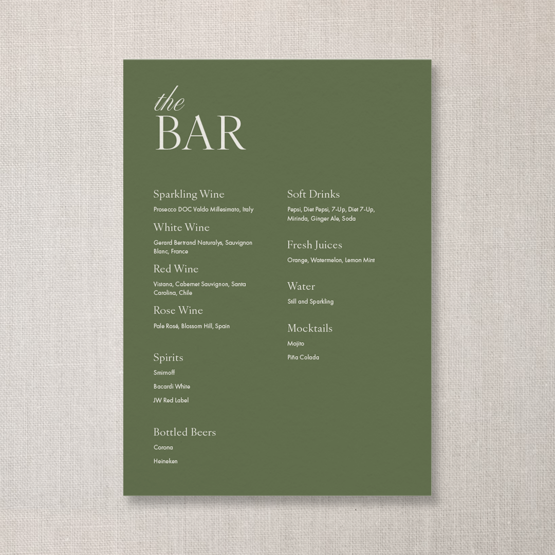A green menu card with white text listing drinks at a bar, including varieties of wine, spirits, bottled beers, soft drinks, fresh juices, water, and mocktails.