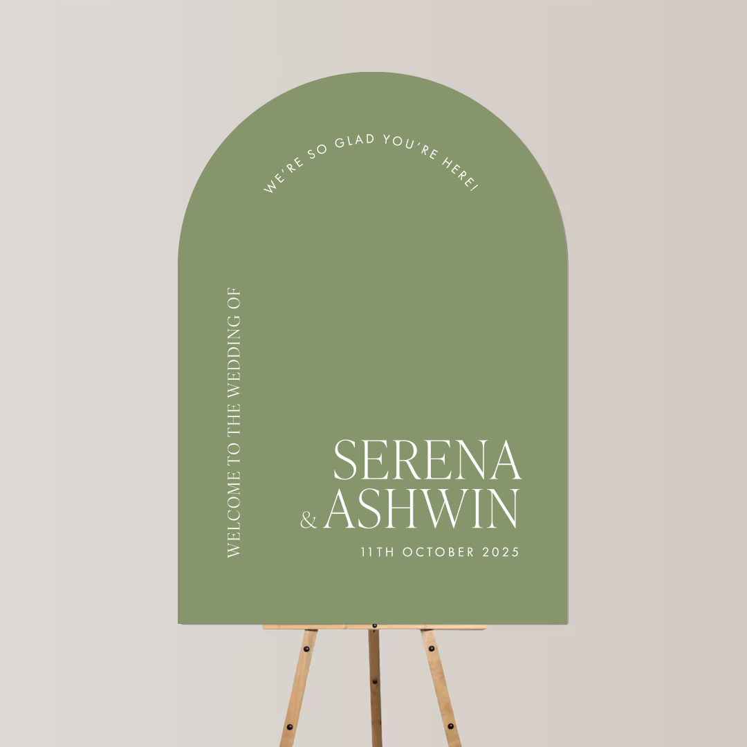Wedding welcome board with green background on easel, displaying the names Serena and Ashwin and the date October 11, 2025.