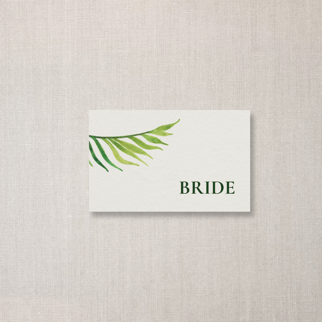 A white card with green watercolor palm leaves in the top left corner and the word 'BRIDE' in dark green capital letters below.