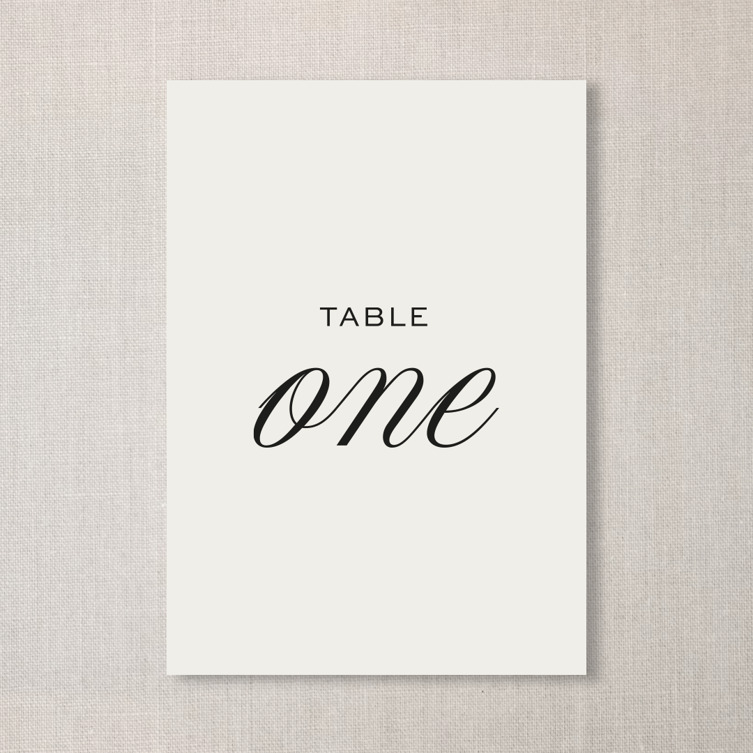 A card on a textured beige background with the words 'TABLE ONE' printed on it, indicating a table assignment.