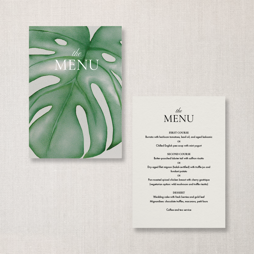 A wedding menu with a green monstera leaf cover on the left and a white sheet with black text listing food options on the right.