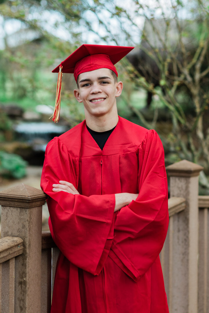 Senior guy cap and gown red half body outdoors