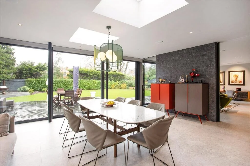 Contemporary open-plan diner with large glazed openings connecting to the garden in a new-build Surrey home.