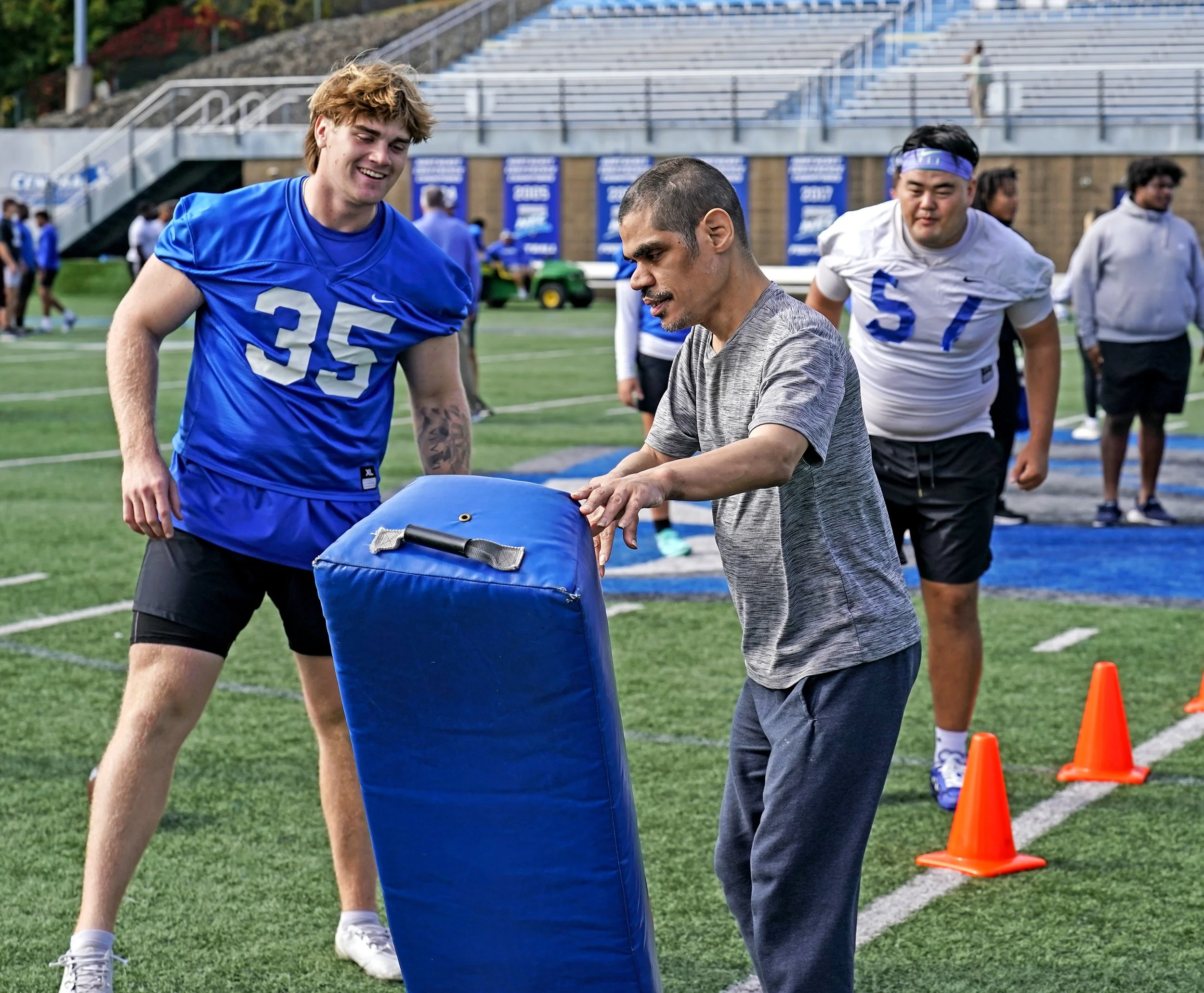 CCSU players with participant tackling dummy