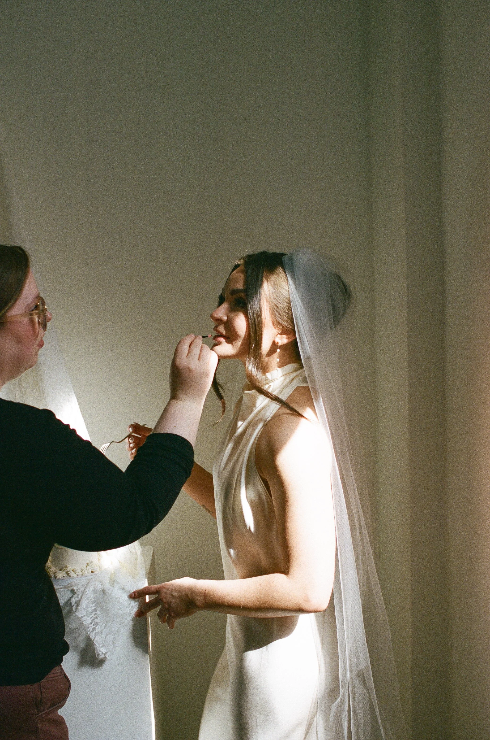 Behind-the-scenes moment of a bride receiving her wedding makeup in a calm, luxurious setting.