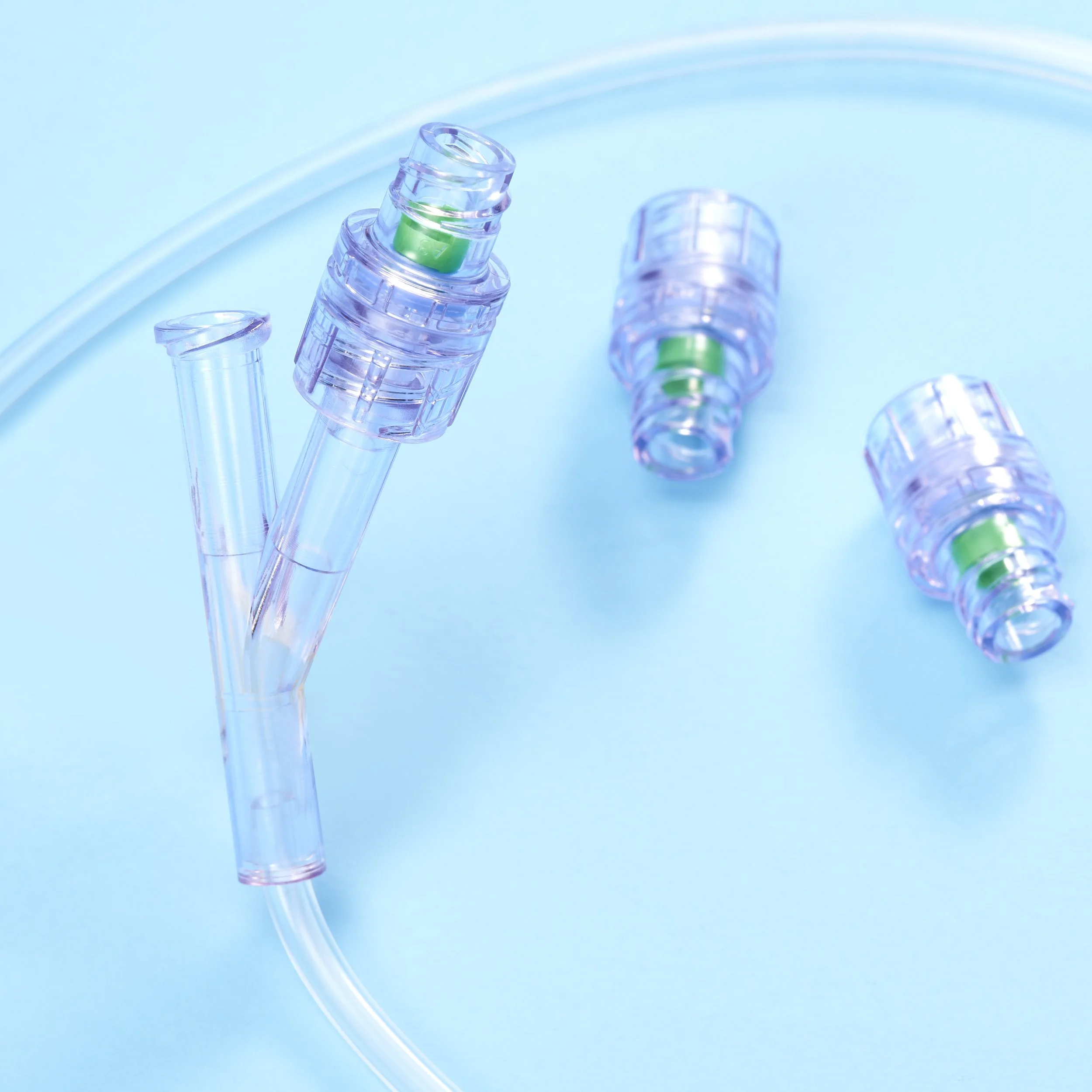 Three clear plastic tubes, two with green components, placed on a light blue background.