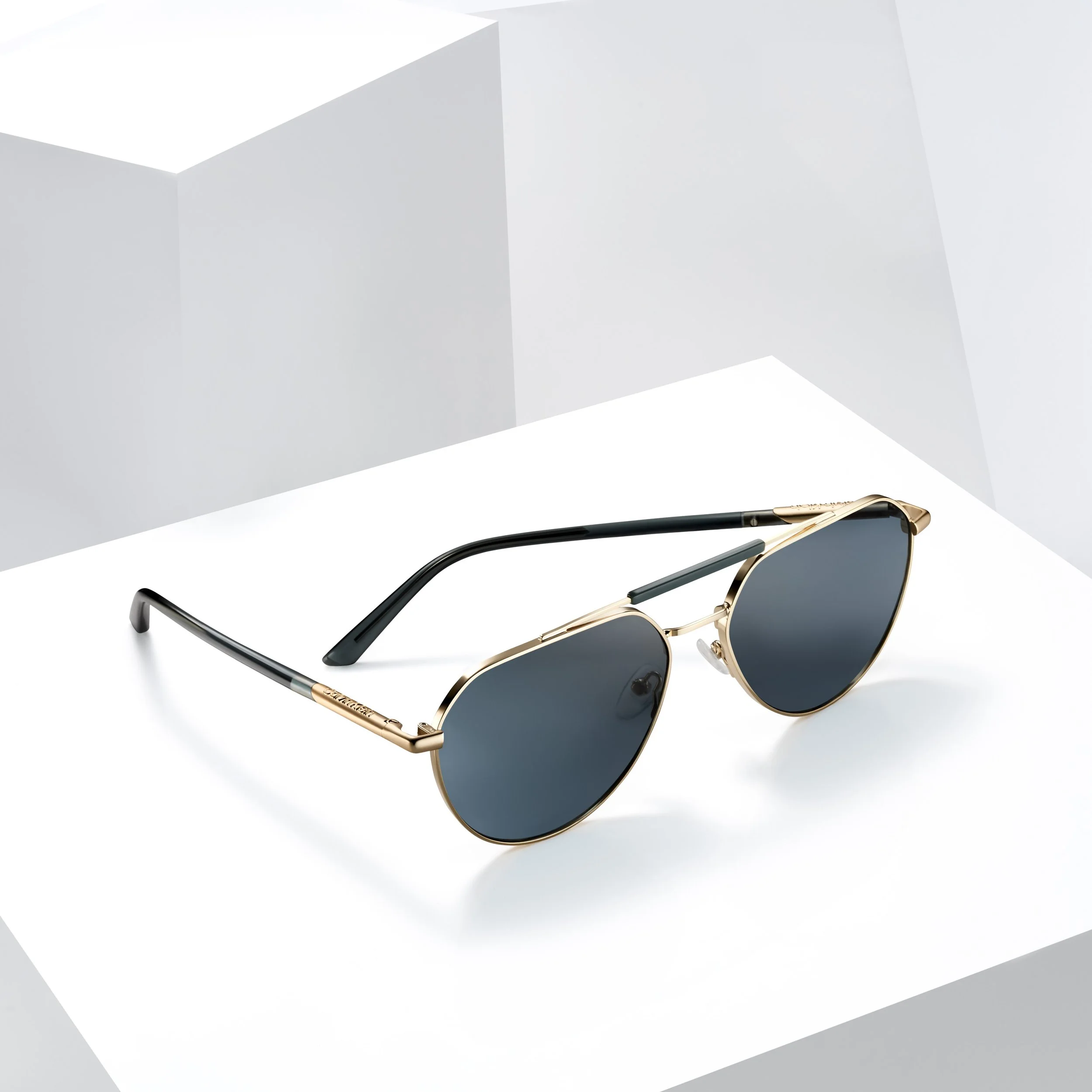 Black sunglasses with gold frames on a white background with a geometric gray and white backdrop.