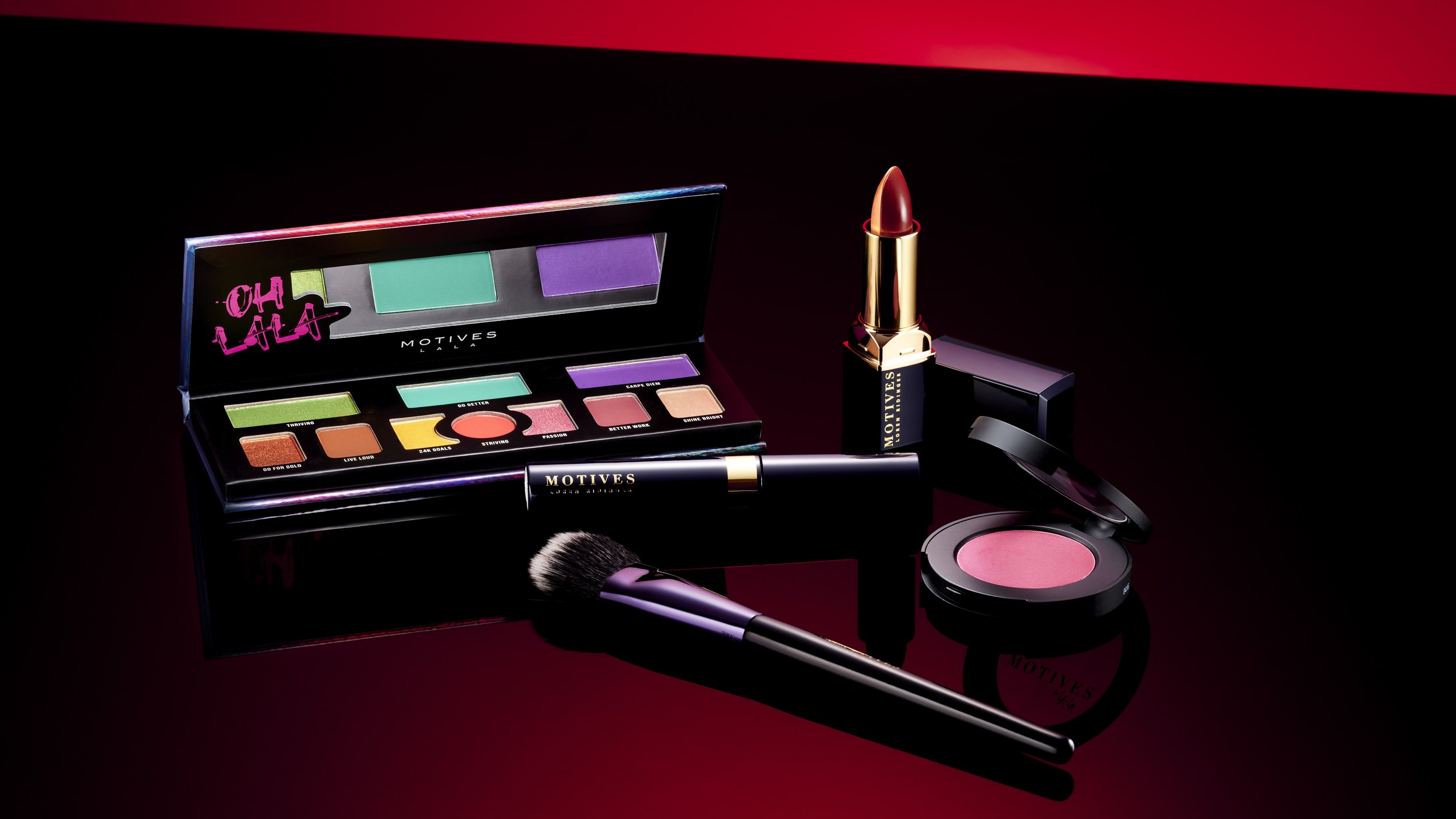 Makeup products including an eyeshadow palette, a lipstick, a blush compact, a makeup brush, and a lipstick pen on a dark red and black background.