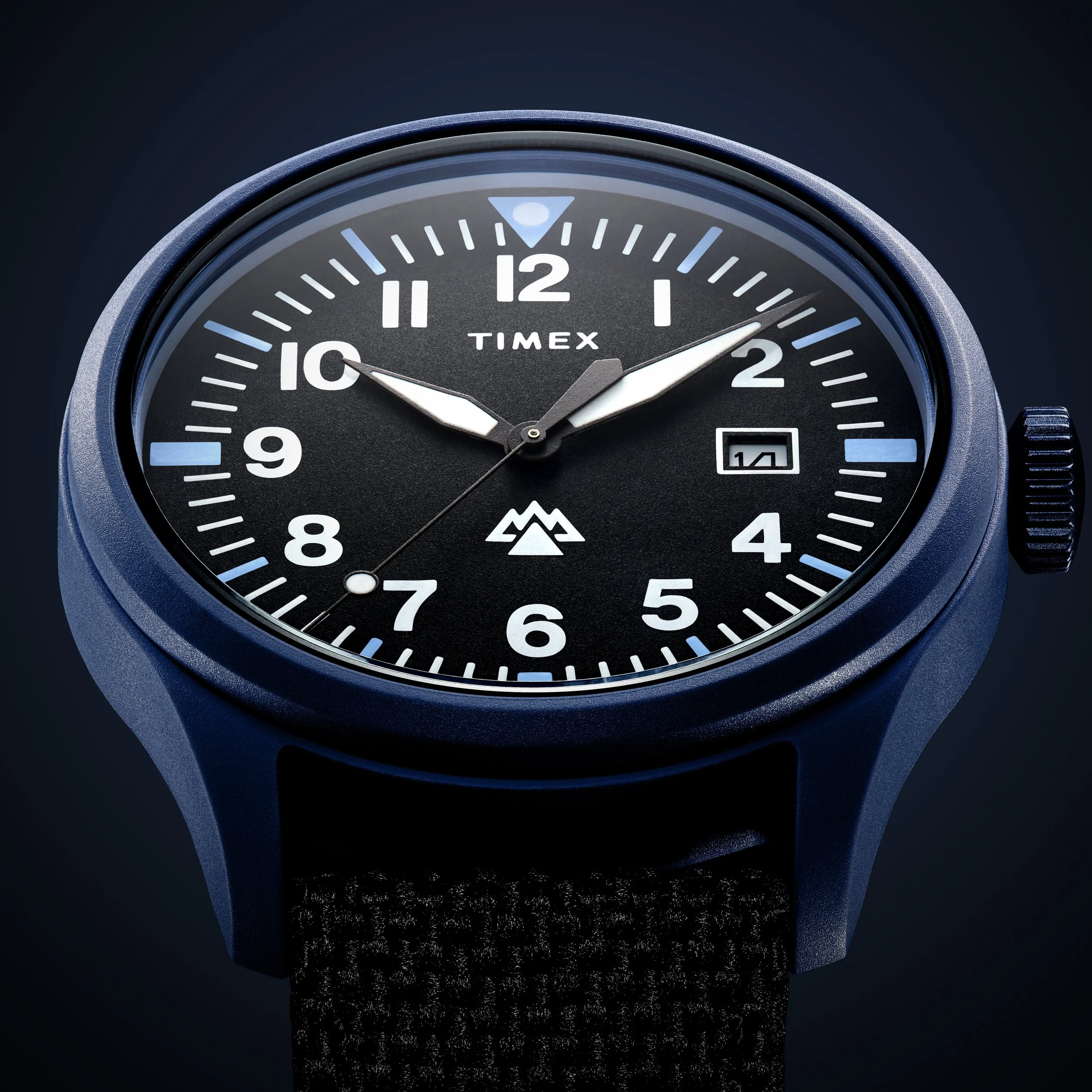 Close-up of a black Timex wristwatch with a blue case and strap, showing the time as approximately 1:49, with a date of the 14th.