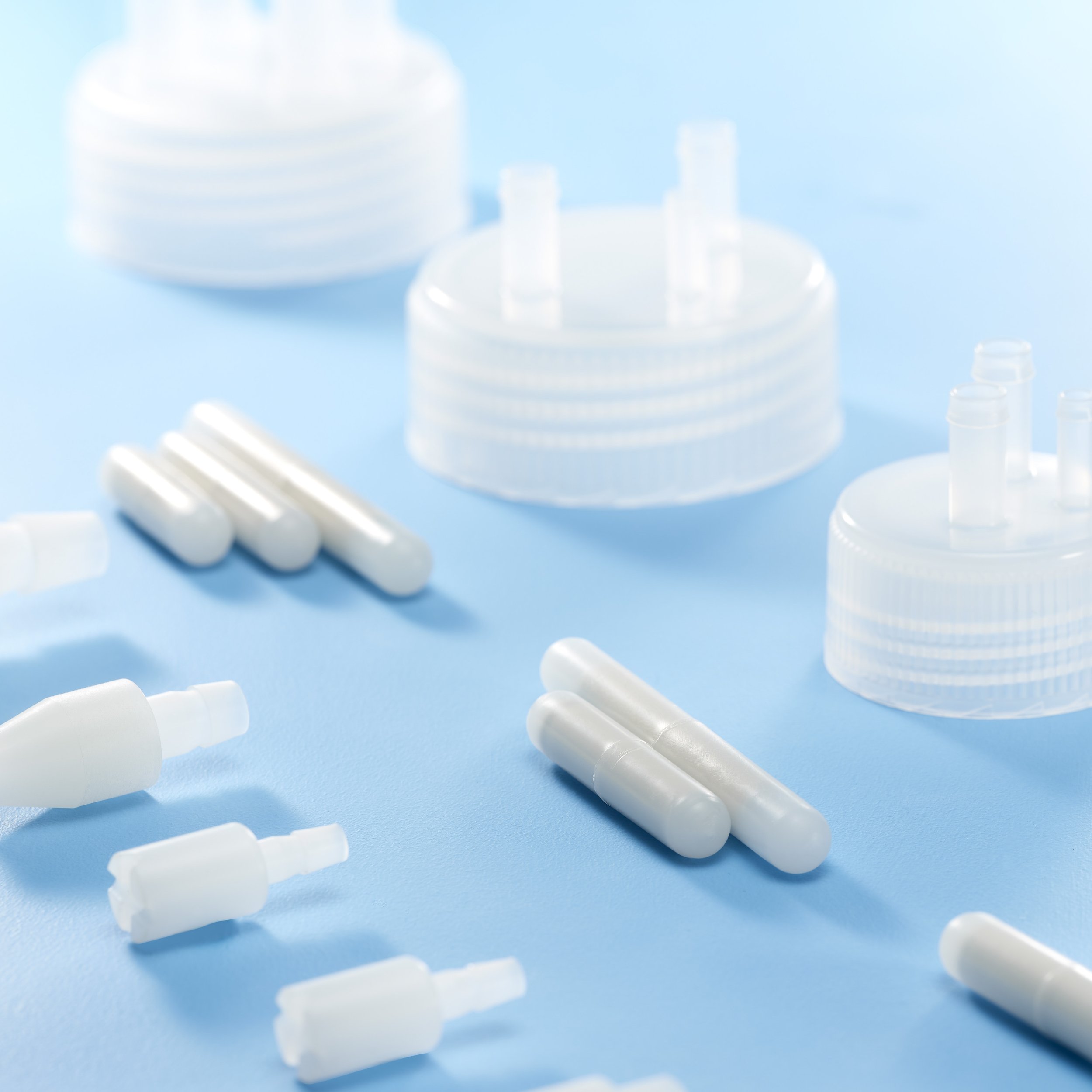 White nasal spray bottles, capsules, and nasal spray bottle caps scattered on a light blue surface.