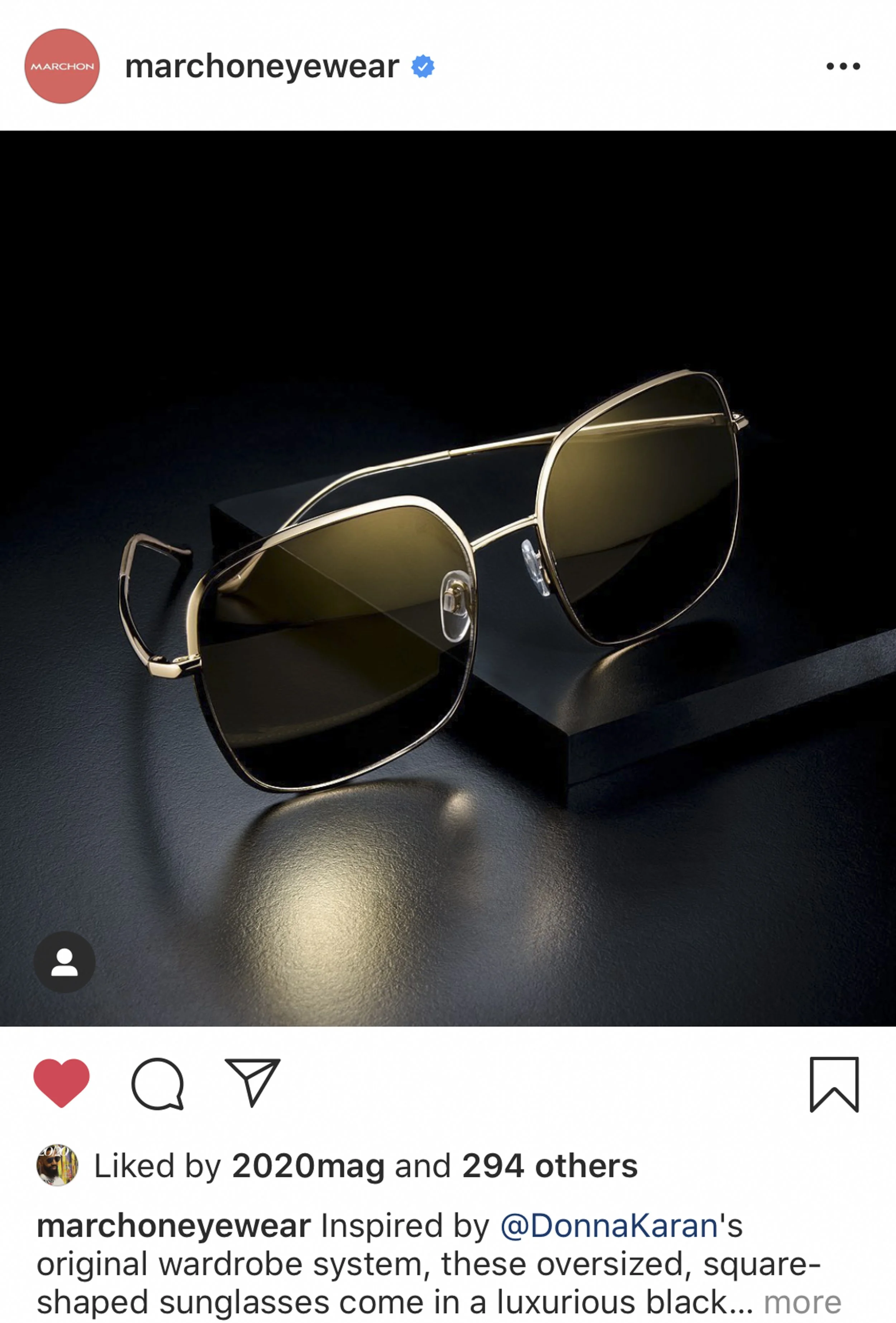 Black and gold oversized square sunglasses with dark lenses placed on a dark surface with a dark background.