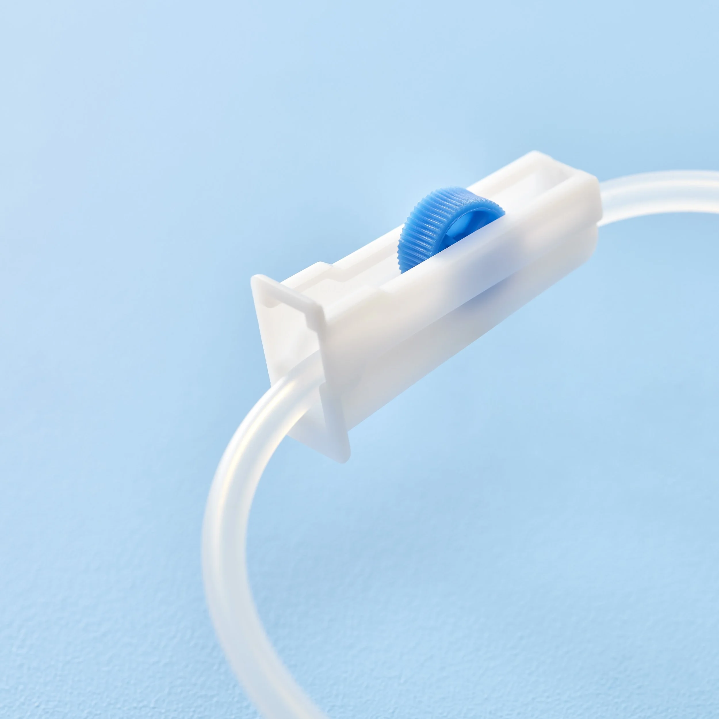 Close-up of a medical IV fluid tube with a white plastic connector and a blue roller clamp on a light blue background.