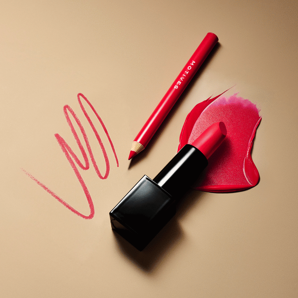 A red lip pencil and a red lipstick with a smear of lipstick color on a beige background.