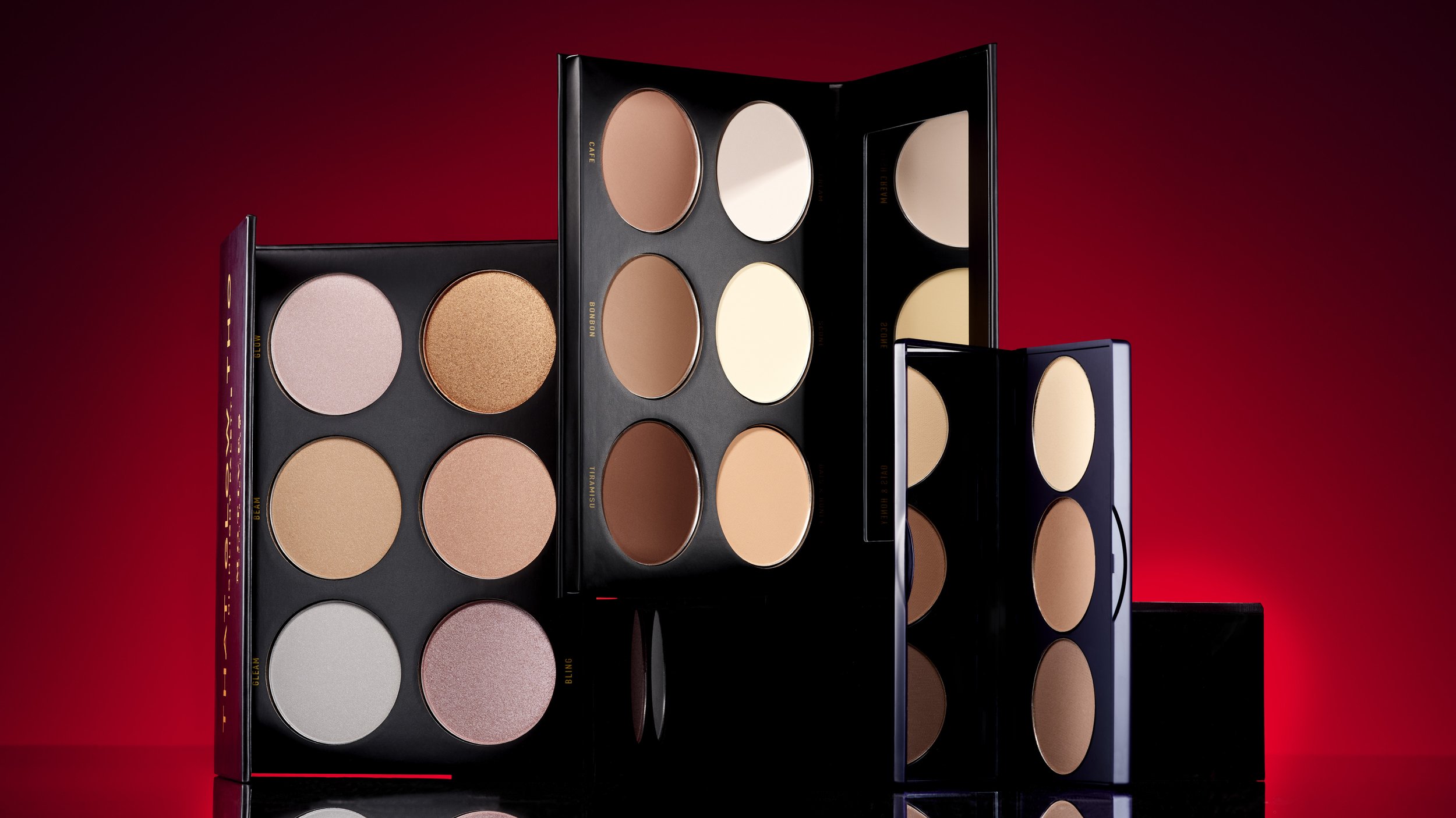 Three open makeup palettes with various shades of powder foundation or blush against a red gradient background.