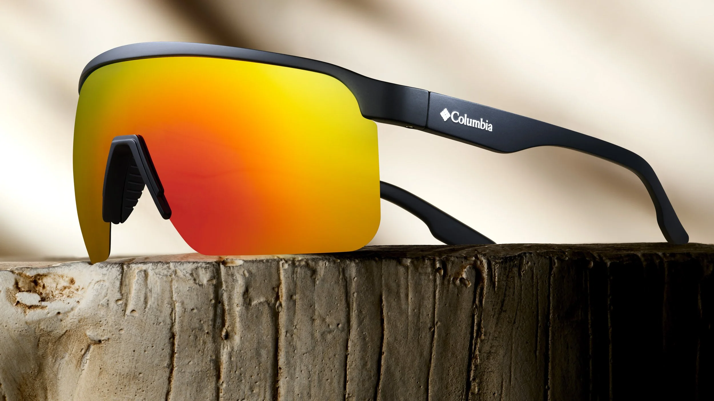 Close-up of Columbia sports sunglasses with orange reflective lenses resting on a weathered wooden surface.