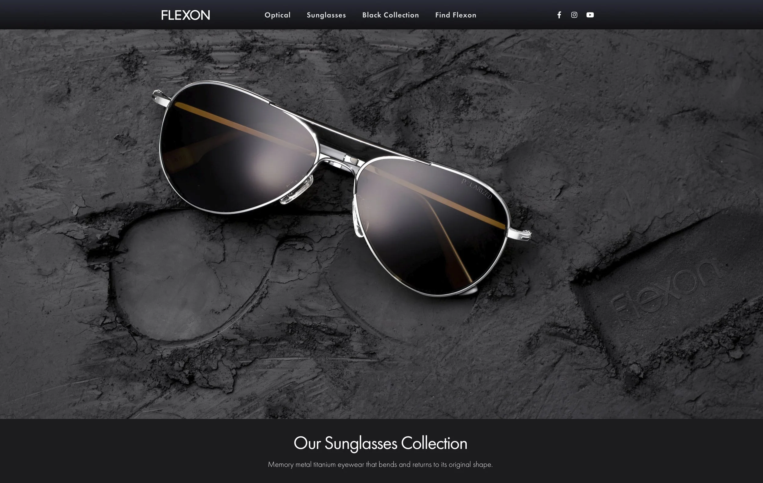A pair of black sunglasses with silver frames on a rough, dark stone surface.