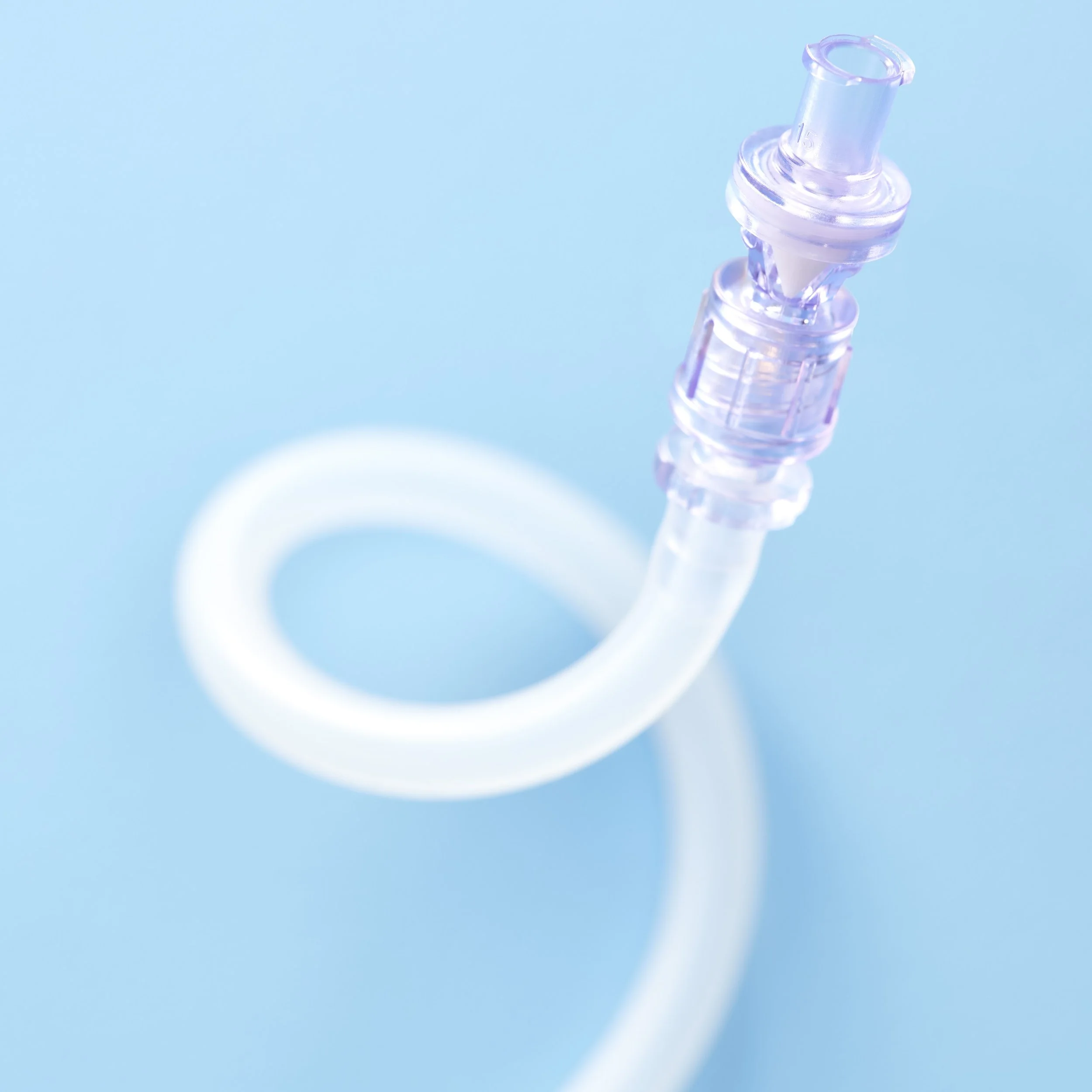 Close-up of a clear medical or laboratory vacuum tube with a flexible silicone tube attached, against a light blue background.