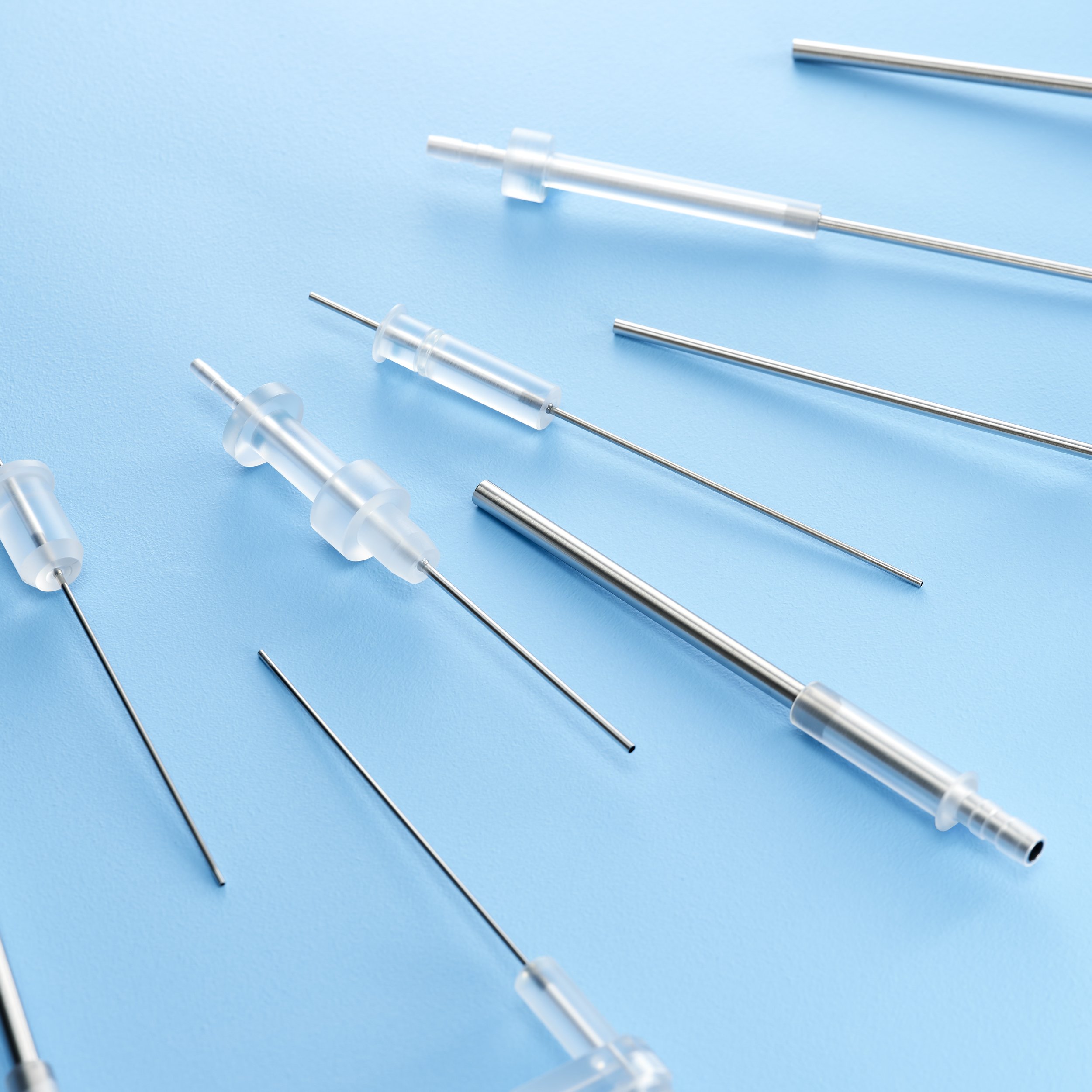 Various medical syringes and needles laid out on a blue surface.