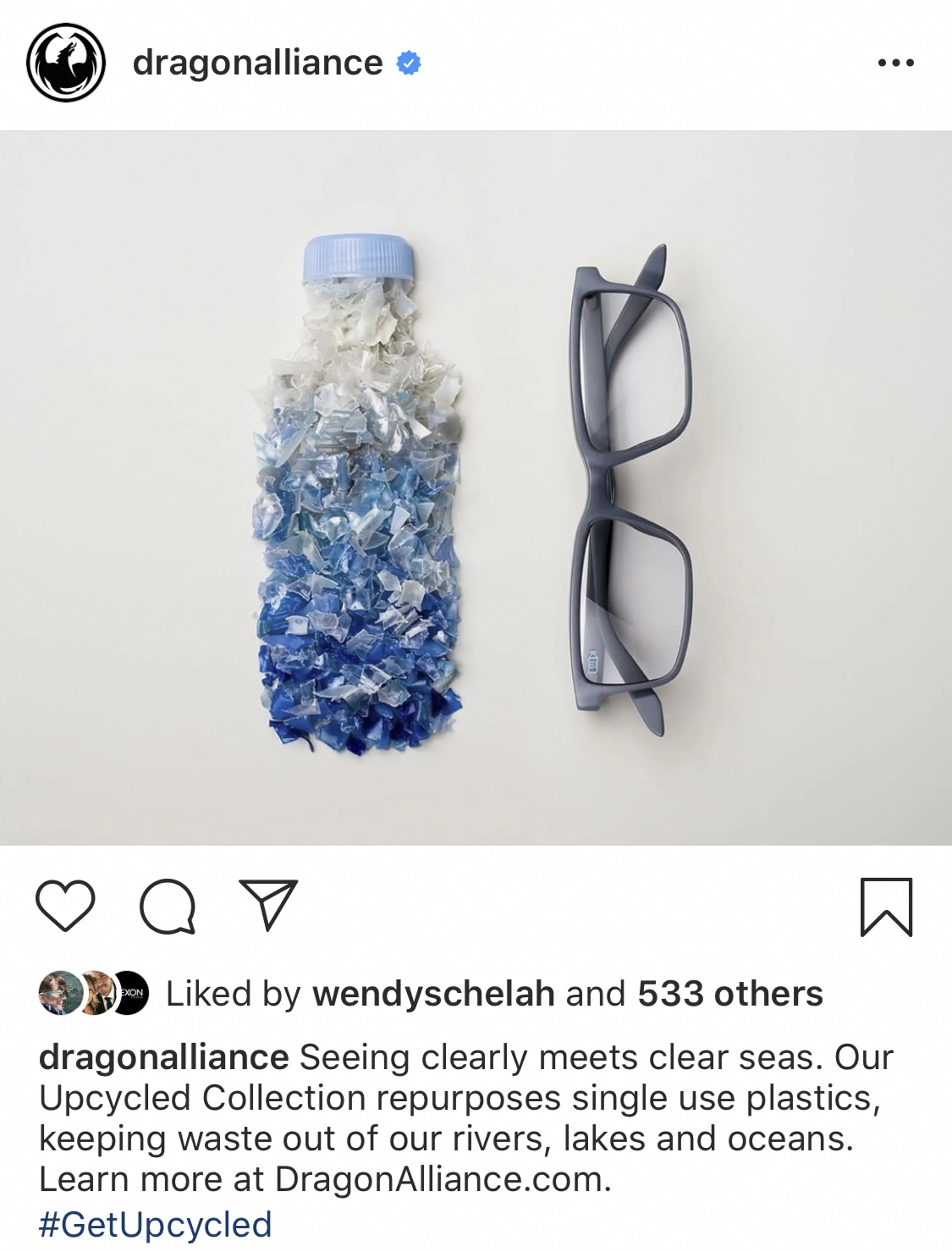 A plastic bottle filled with shredded plastics in white and blue shades, next to a pair of gray glasses on a white background.