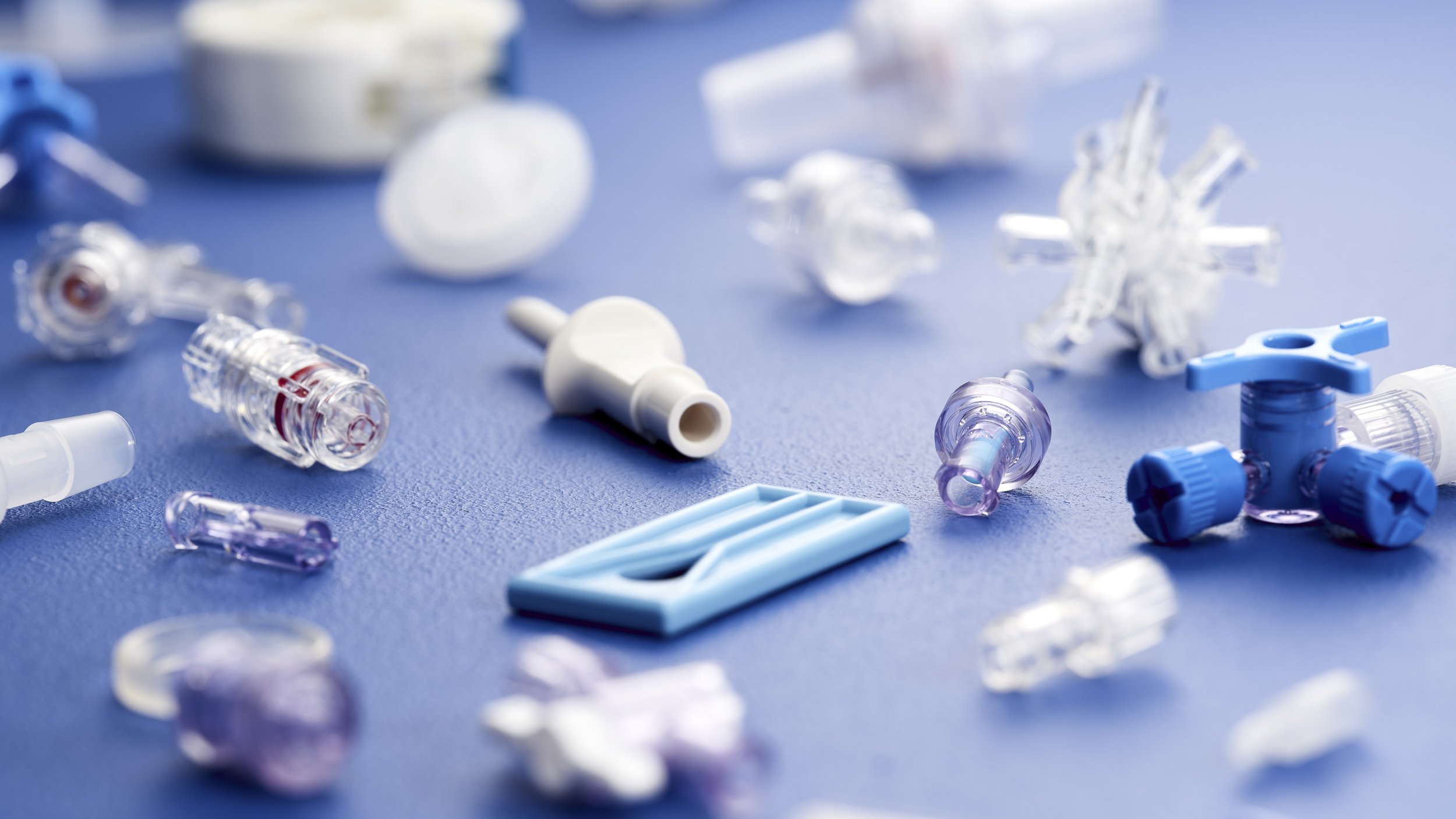 Various medical device parts and tubing scattered on a blue surface.