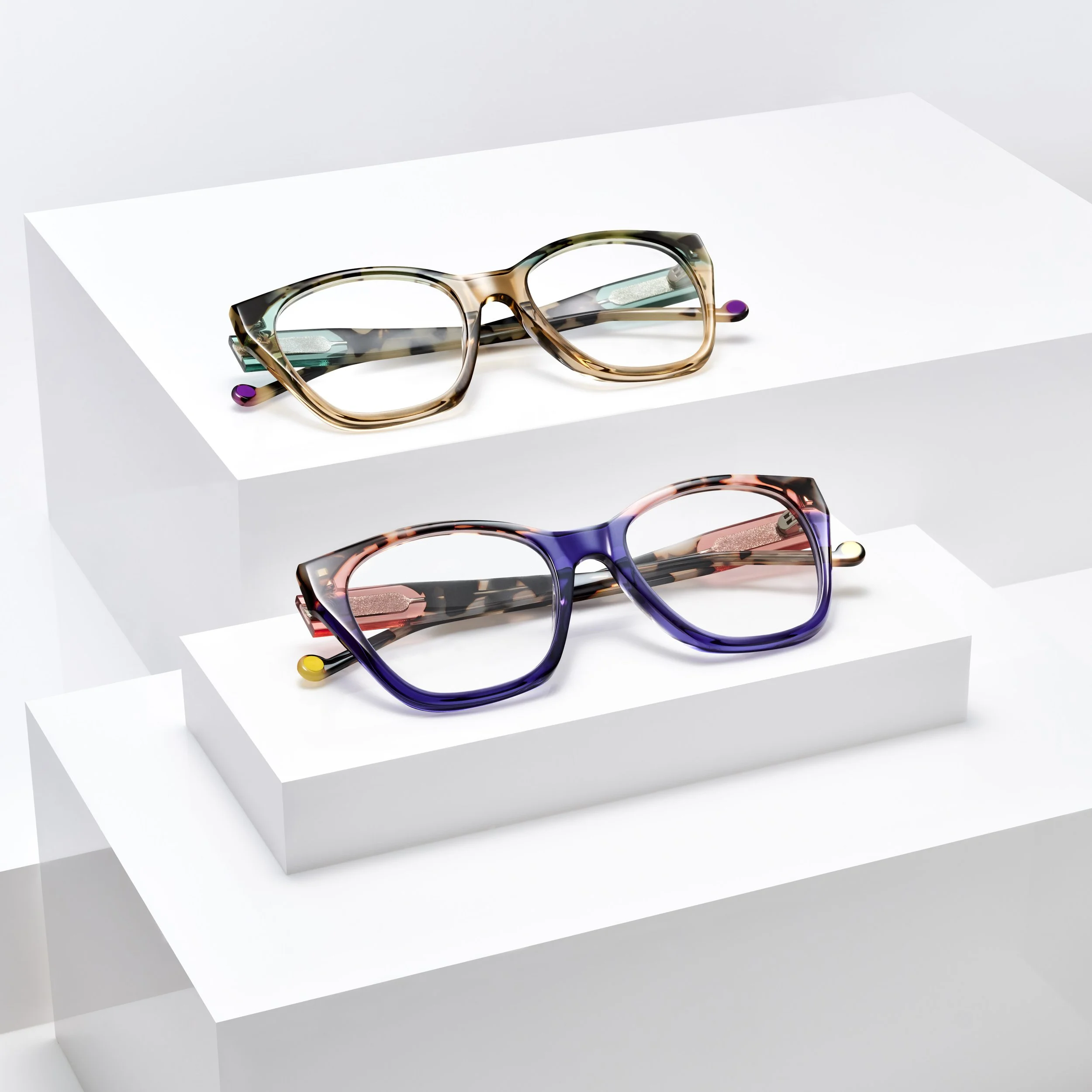 Two pairs of eyeglasses, one with multicolored tortoiseshell frames on a white platform, the other with purple tortoiseshell frames on a white platform, against a white background.