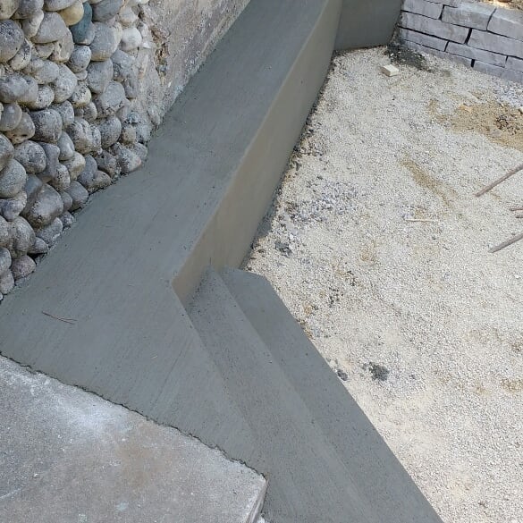Concrete steps in front of a paver patio by big cedar lake