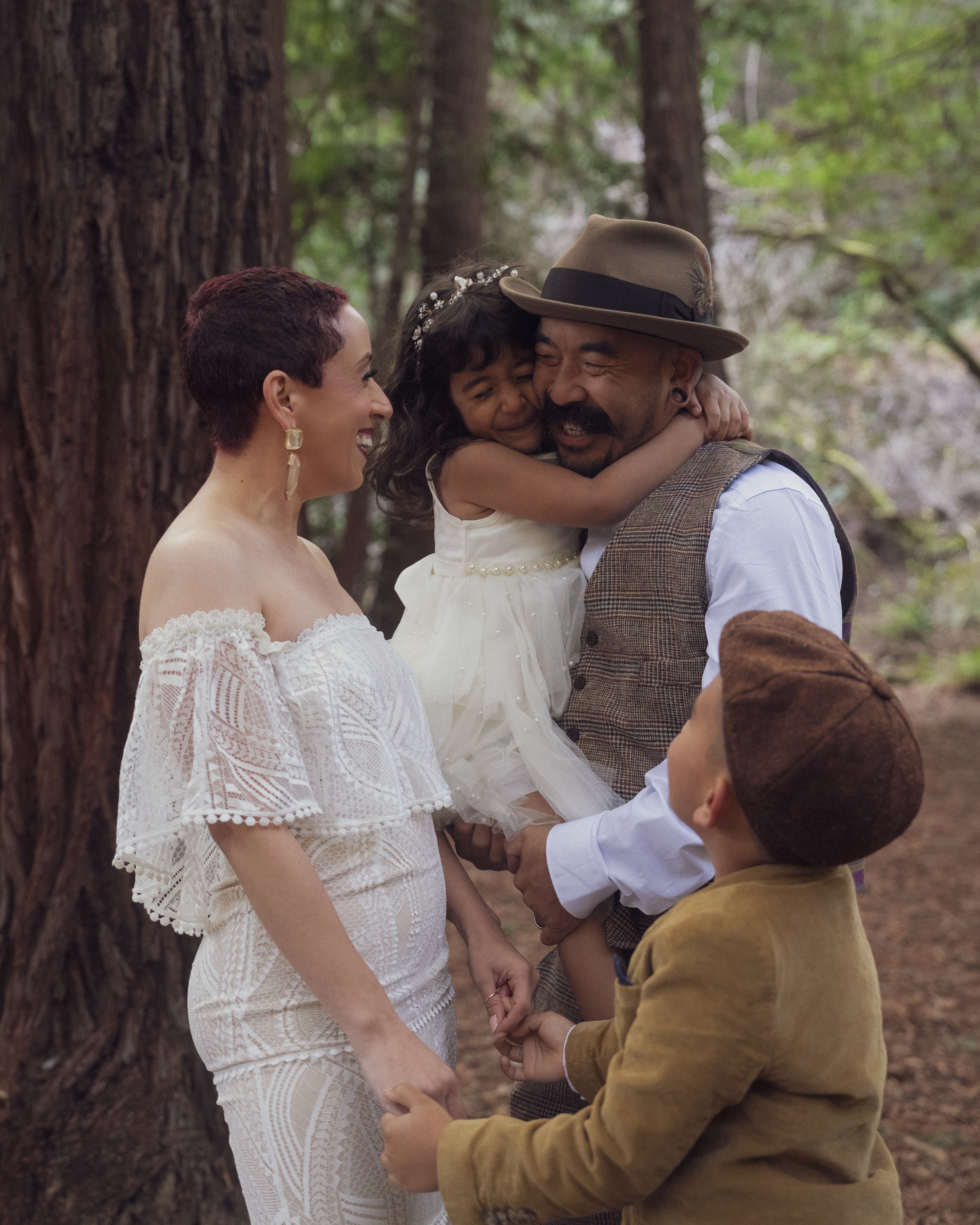 Capture the essence of family love in this enchanting forest setting with our Family Portrait Photography. This image showcases an Outdoor Wedding Photoshoot where the beauty of nature enhances the emotional family moments. The bride is adorned in a