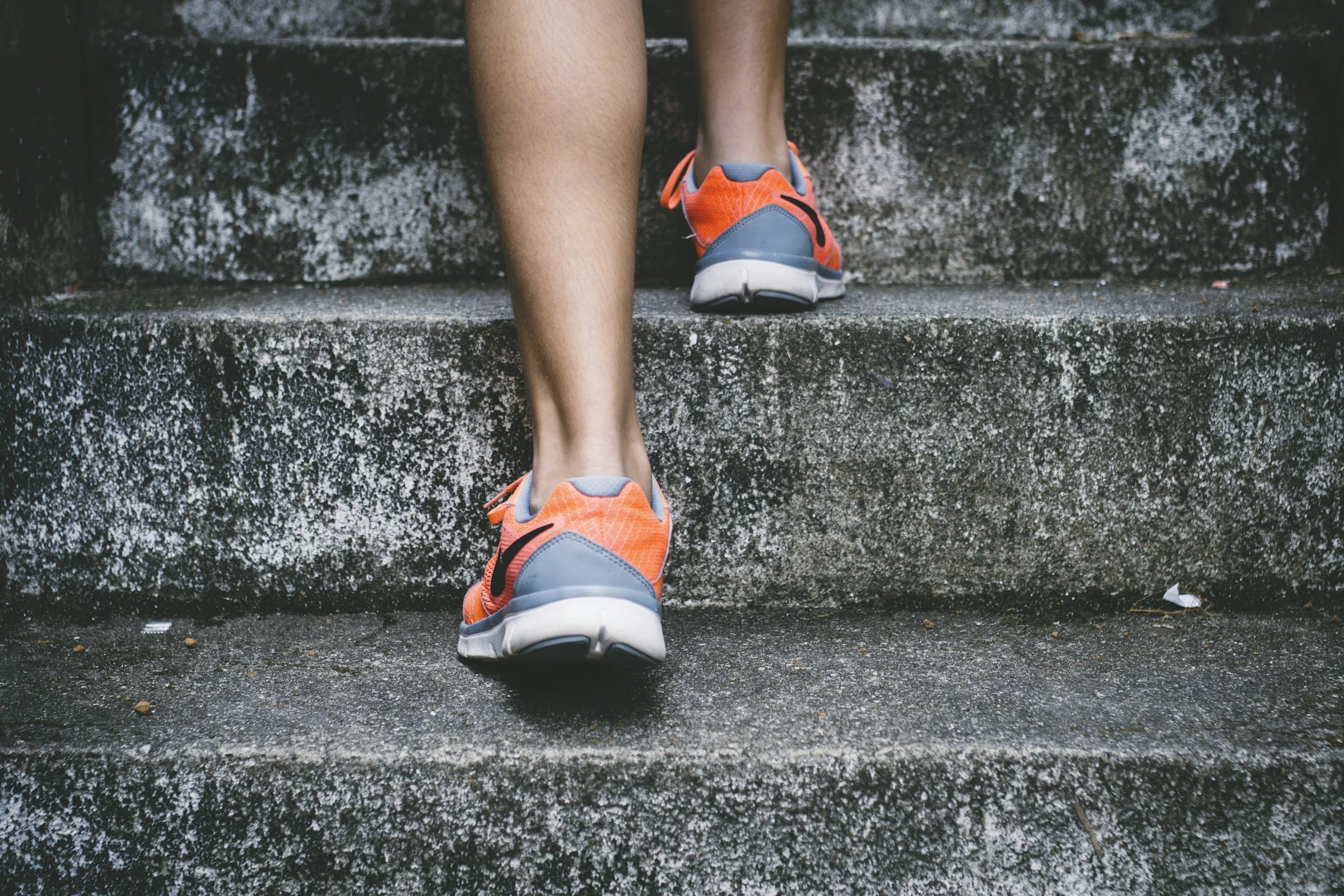 A person developing healthy habits exercises outside by walking up steps