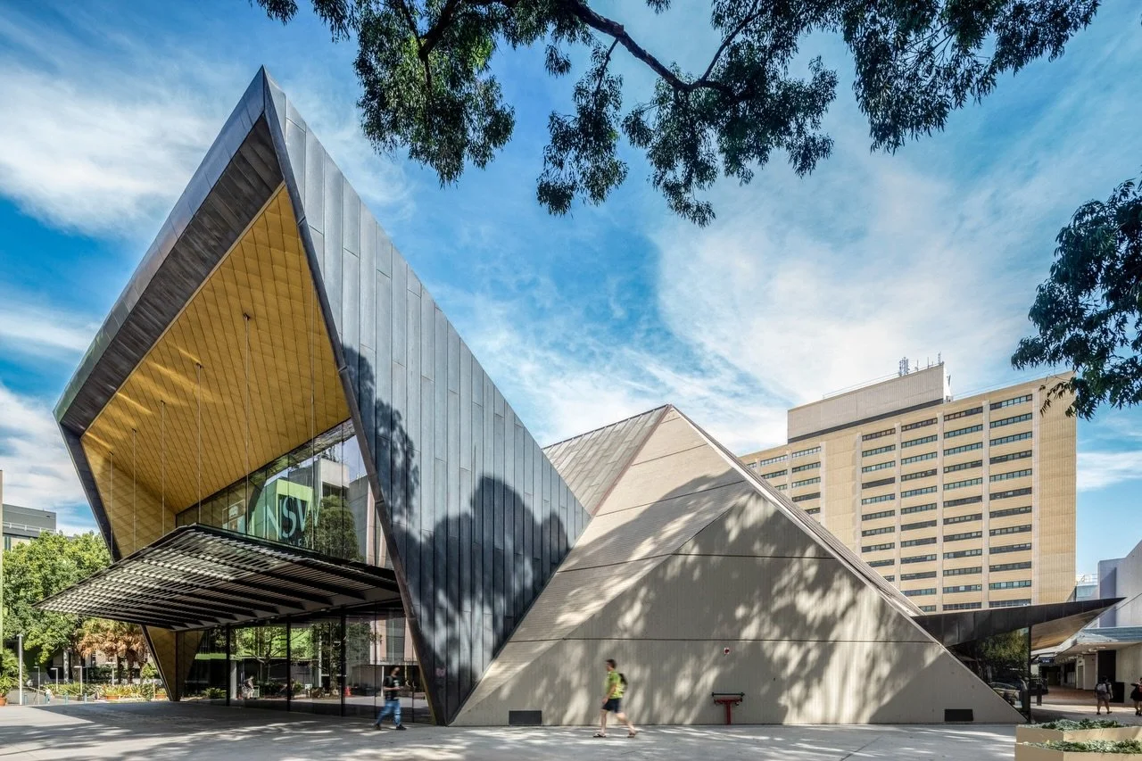 then &amp; now.

Located on Bedegal Land, the Sir John Clancy Auditorium was designed in the 1970&rsquo;s with a strong sculptural form representative of its brutalist era.

The project objective was to expand the capacity of an undersized foyer, max