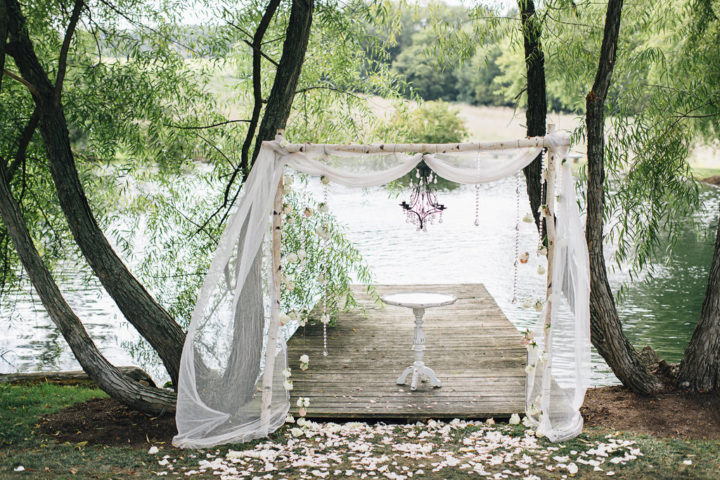Loved this wedding ceremony arbor with hanging chandelier, crystals, and flowing fabric!