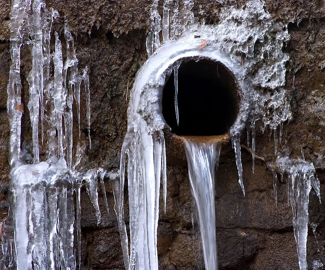 A frozen pipe with icicles hanging from it.