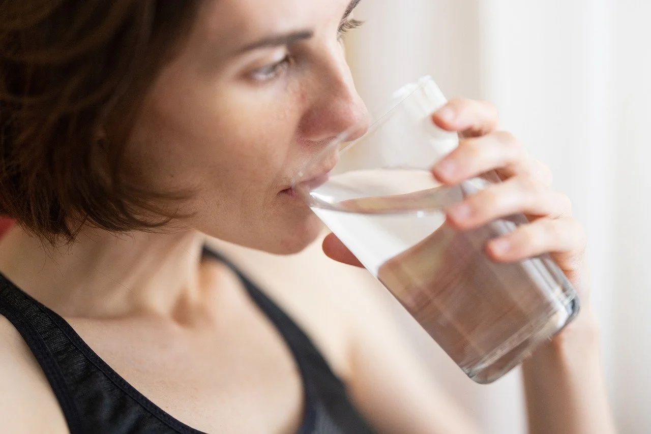 A woman with short brown hair drinking a glass of water.