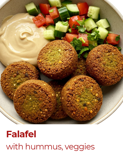 Falafel balls served with hummus and a fresh cucumber and tomato salad in a white bowl.