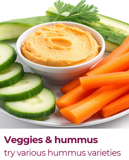 A plate of fresh vegetables including sliced cucumbers, carrot sticks, cucumber slices, and a bowl of hummus garnished with a sprig of parsley.